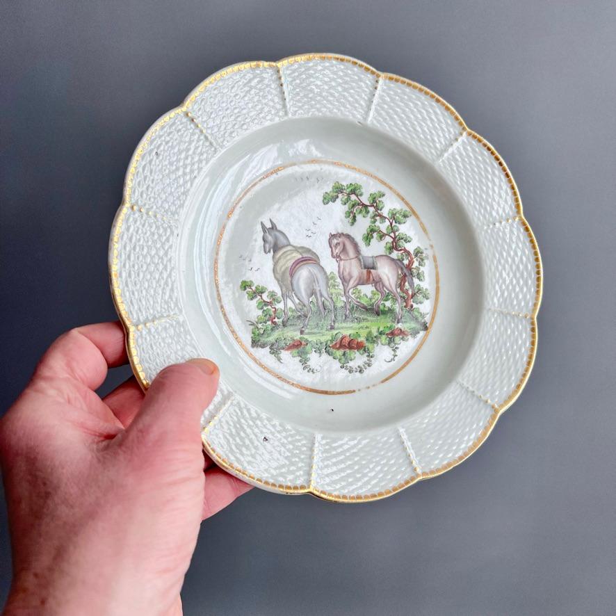 This is a very rare deep plate made by Worcester around 1780. The plate has a basket weave rim and a very charming image of the Aesop fable of the horse and the donkey in the centre. The image is painted in the style of Jefferyes Hamett O'Neale, who