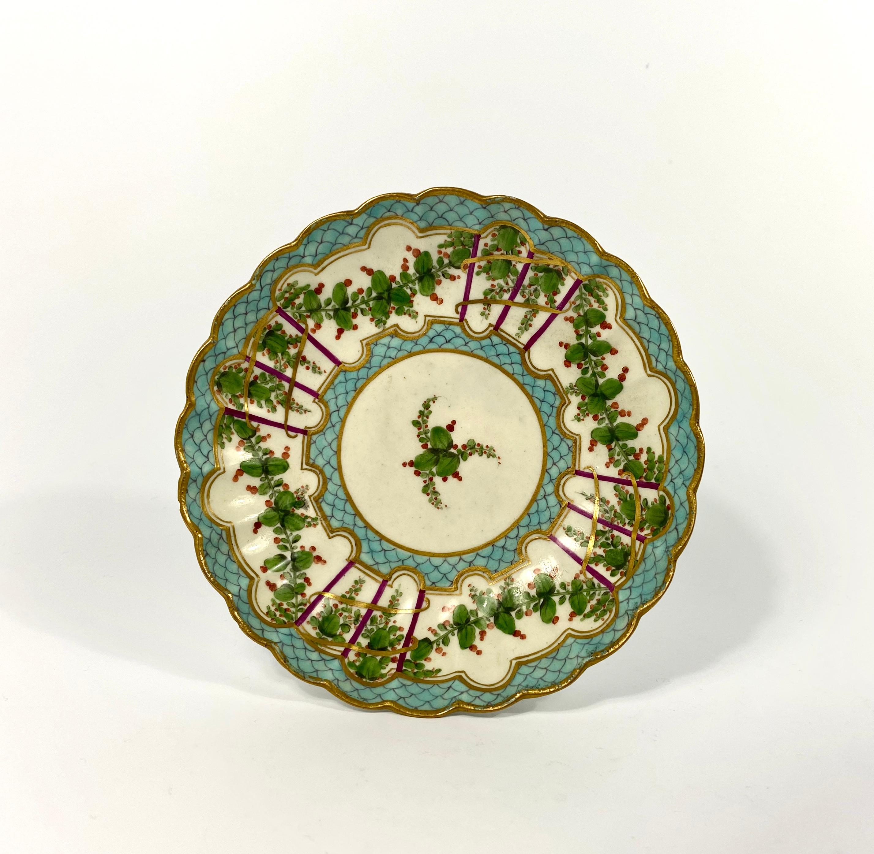A fine Worcester porcelain teabowl and saucer, circa 1770. Both fluted items, beautifully decorated in Sèvres style, with continuous bands of berries growing on vine, suspended from trellis. Having turquoise ‘scale’ borders, heightened with