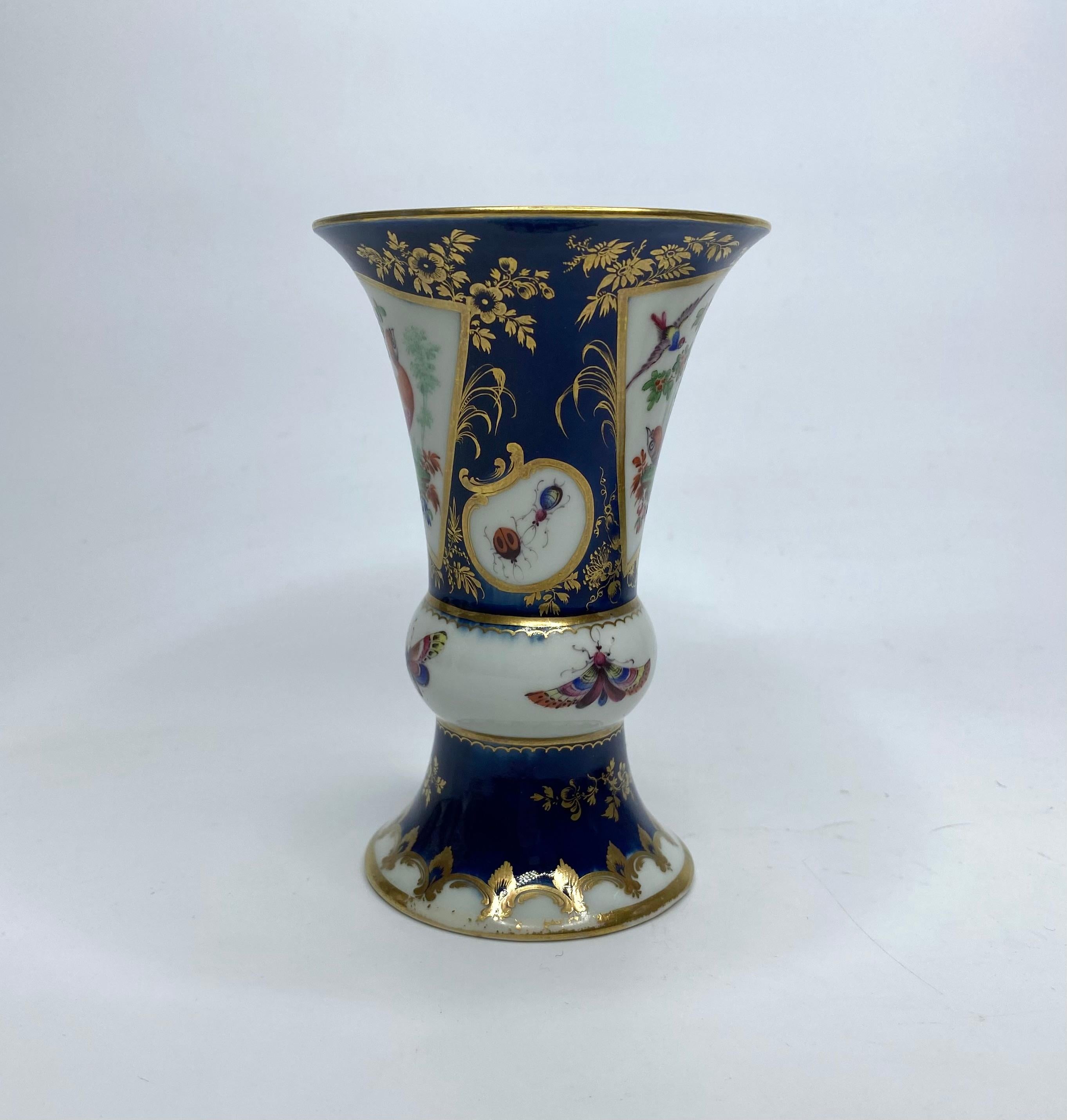 First Period Worcester porcelain vase, c. 1770. The vase modelled after a Chinese ‘Gu’ shaped vase, and finely painted with fan shaped gilt panels of ‘Fancy Birds’, amongst trees. Divided by smaller panels containing moths and insects. All upon a