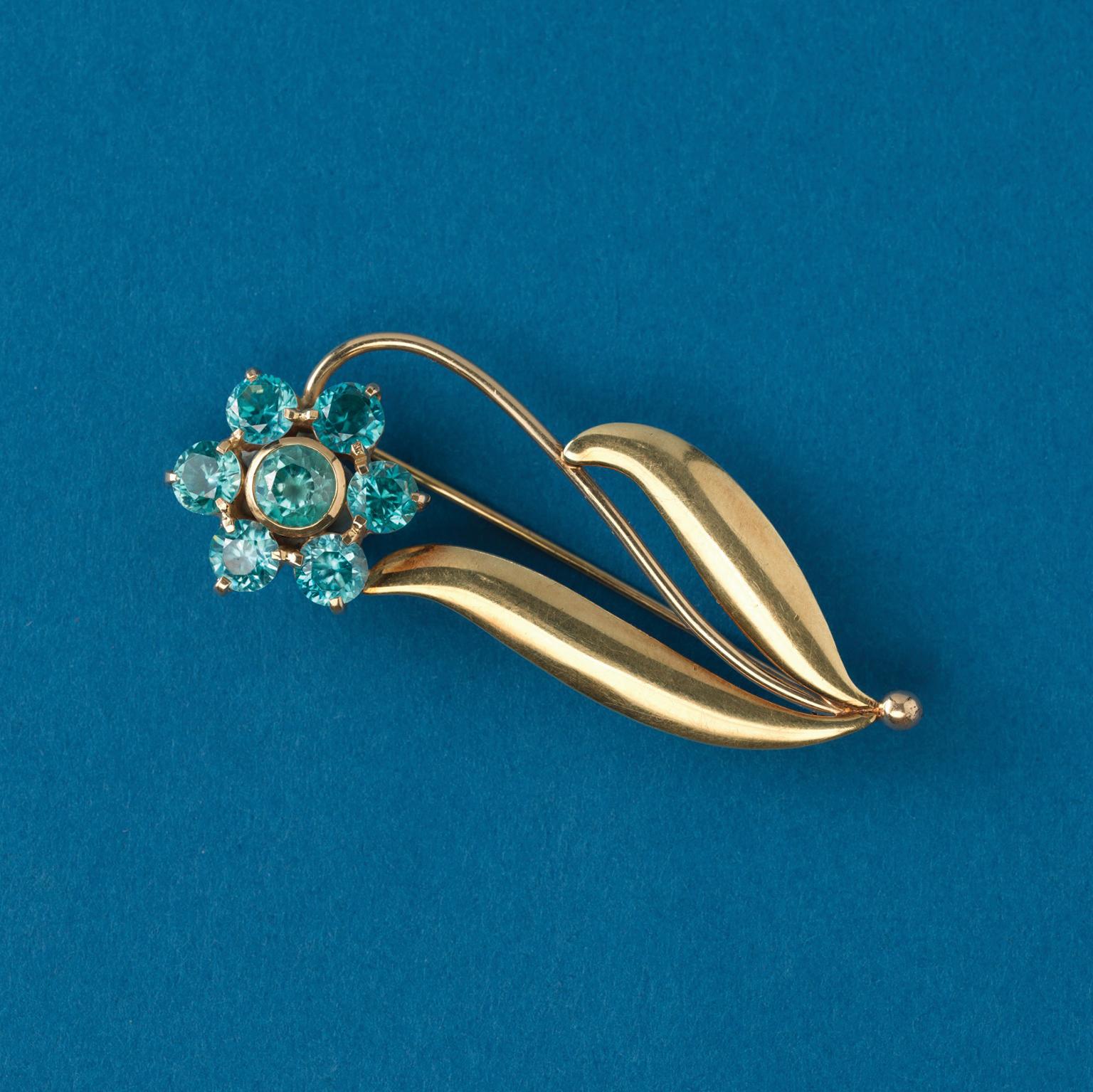 A 14 carat gold flower brooch set with 7 round, bright blue zircons, signed WAB, Wordley, Allsopp & Bliss American, circa 1945.

weight: 6.29 gram
dimensions: 5.8 x 2.3 cm