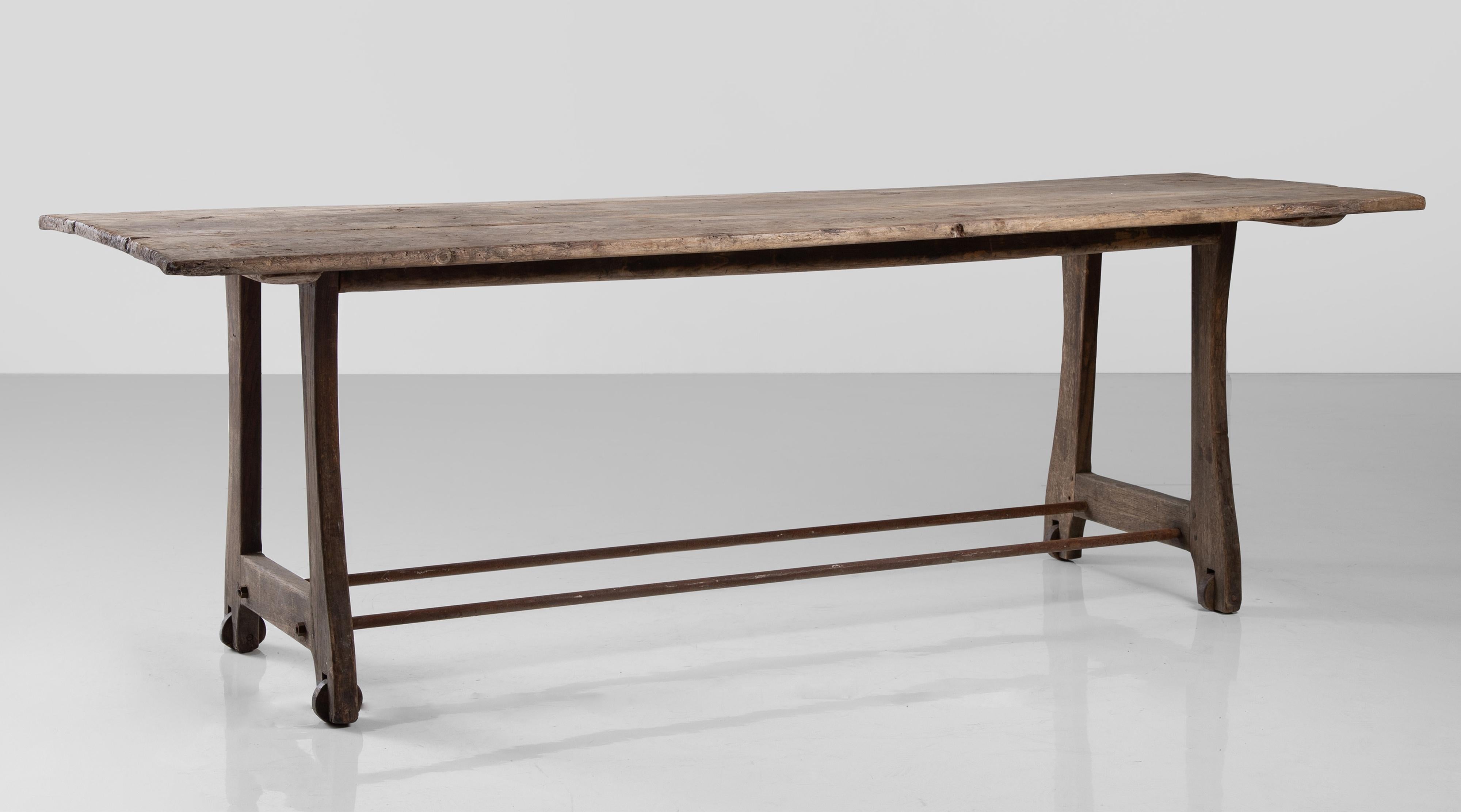 Unique work table with wooden wheels.
France circa 1900.
Plank top oak table / console with iron stretchers.
Measures: 89” W x 31.5” D x 29.75” H.
 
