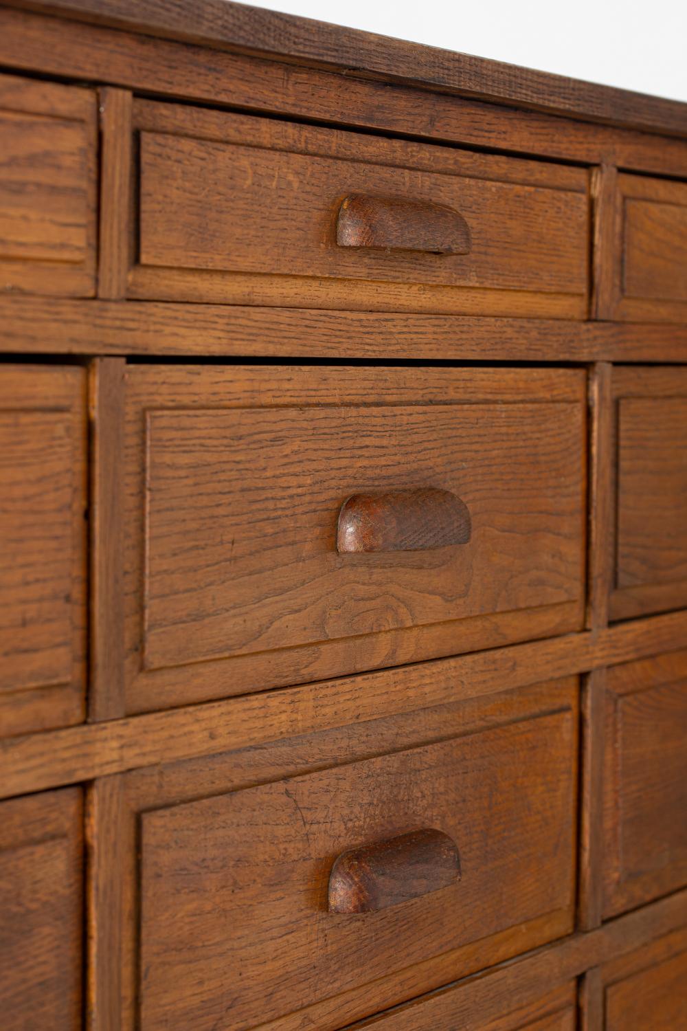 Rare workshop or pharmacy cabinet in solid oak with eighteen drawers, France, circa 1930.