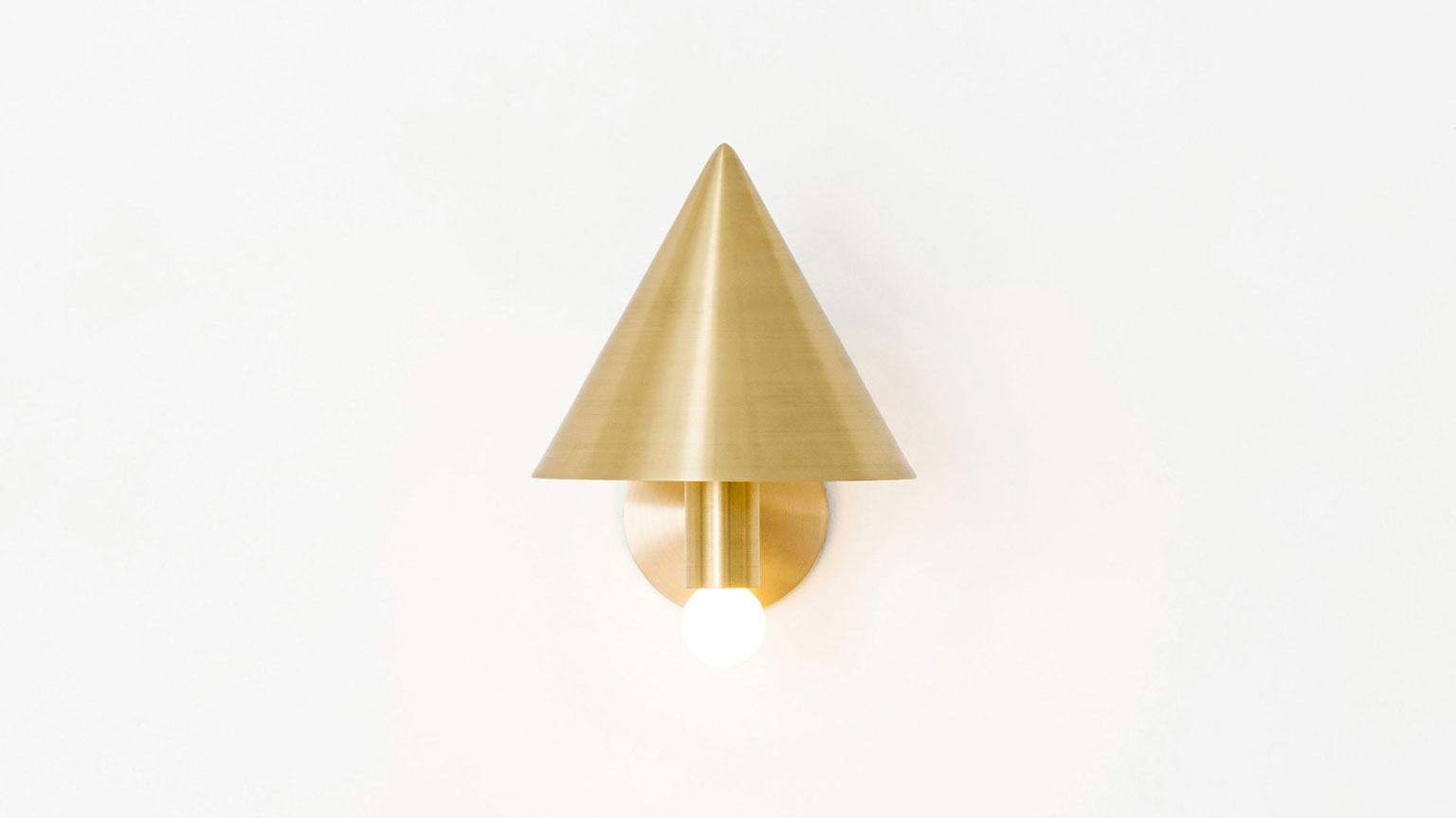 The canopy sconce deconstructs the conventional wall sconce into a series of expressed, geometric relationships. A bold conical shroud rises above a softly glowing bulb creating a canopy of diffused reflection. UL listed. Damp rated upon request.