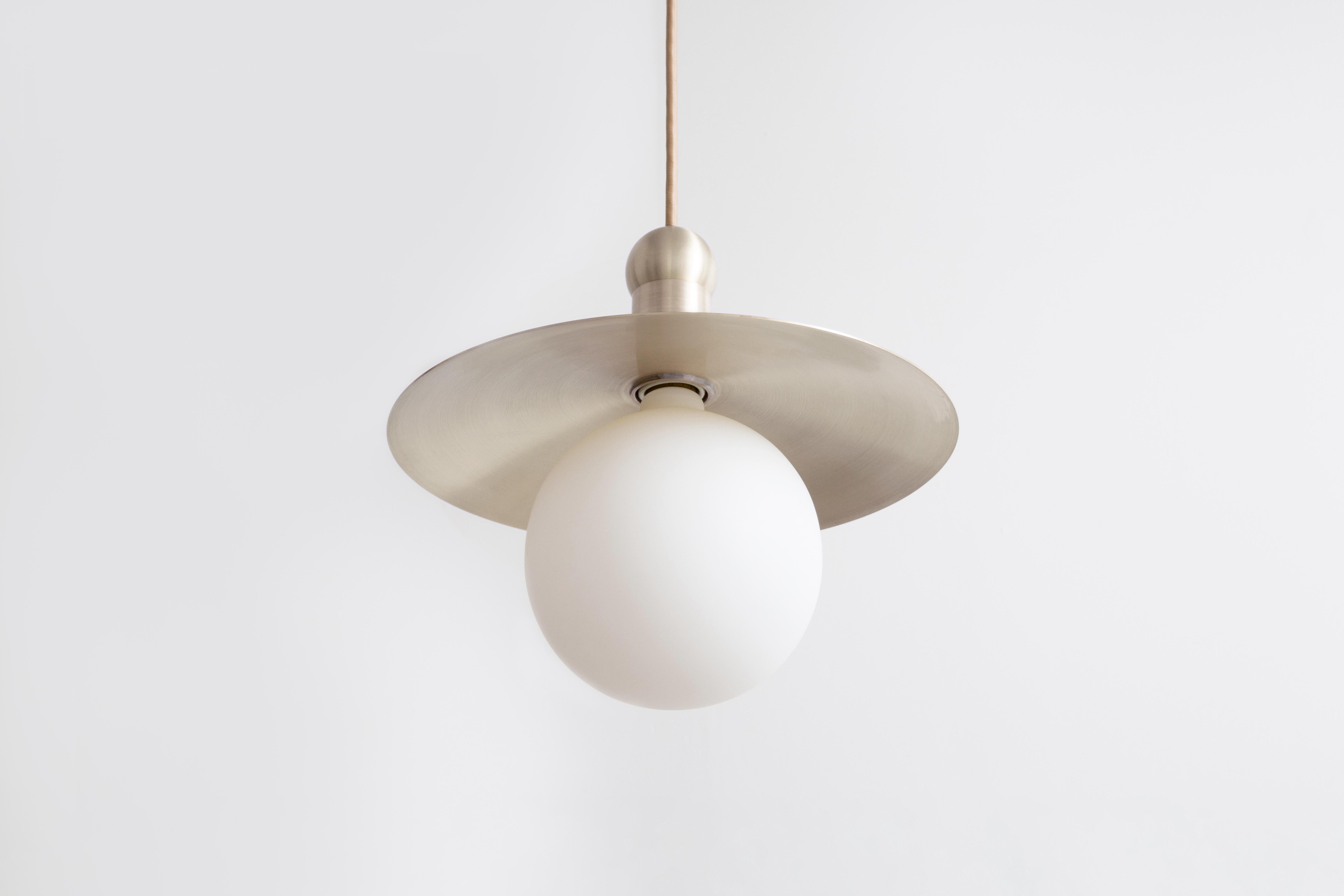 The Helios cord pendant positions a single glowing bulb against a stationary radiant dish, exploring the scale and illumination of an early American candle via the form of a traditional down-light pendant. With rotund details, each pendant provides
