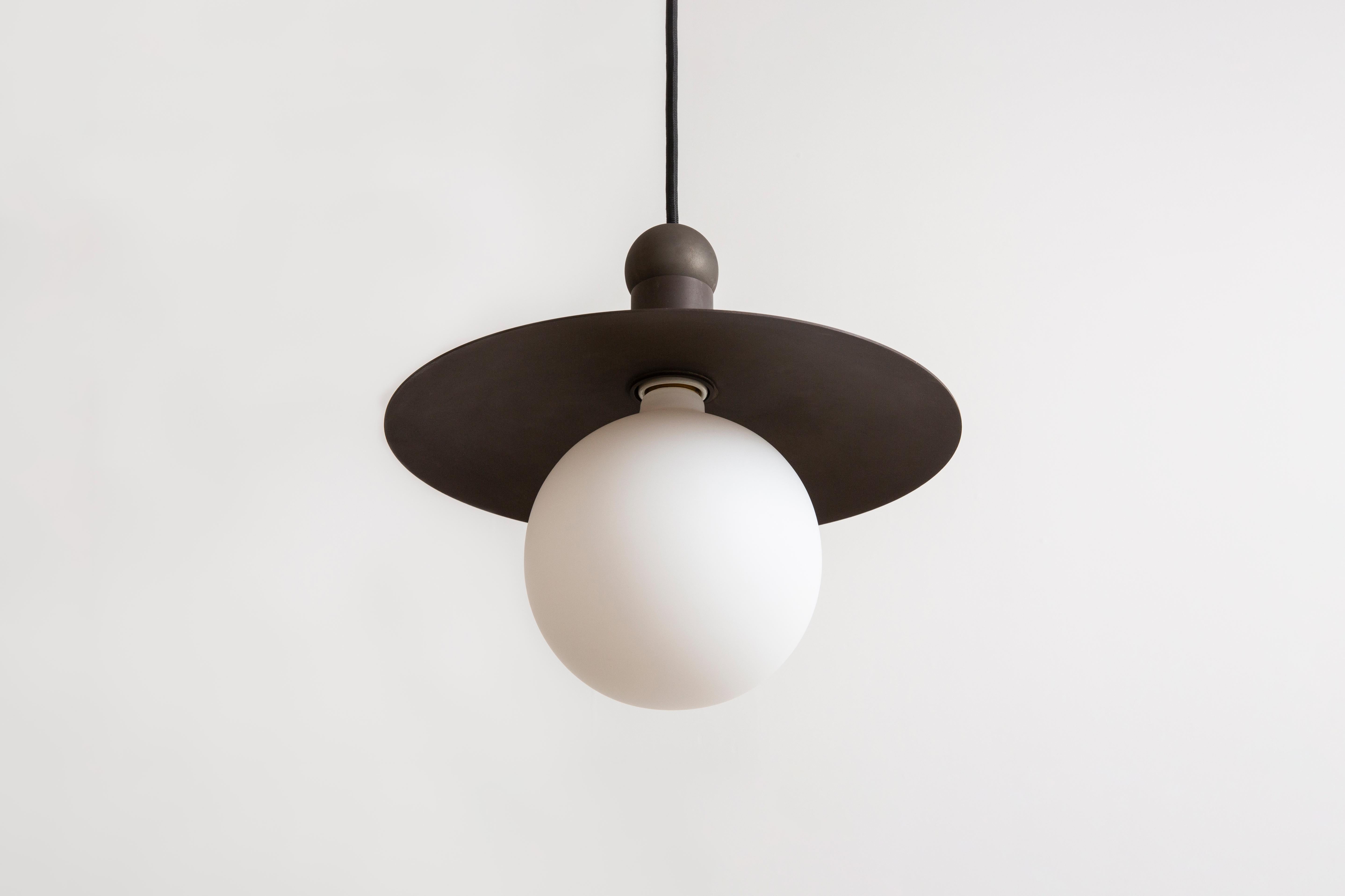 The Helios cord pendant positions a single glowing bulb against a stationary radiant dish, exploring the scale and illumination of an early American candle via the form of a traditional down-light pendant. With rotund details, each pendant provides