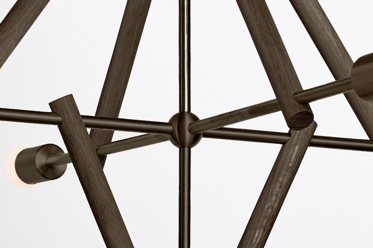The lodge chandelier five is a network of wooden frames that support a delicate structure for light. The play between wood and metal emphasizes the counterpoint between structure and network. Made in the USA, UL listed.