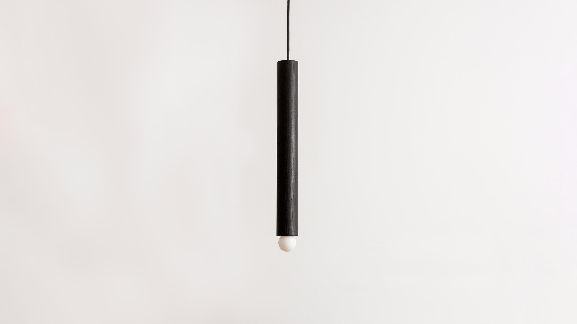 The Lodge cord pendant large is crafted from a hand-turned oak dowel in our linear length. Suspended from a cloth cord, the wooden dowel is a tactile armature punctuated by a single glowing bulb. Available in natural oak or oxidized ash with hewn