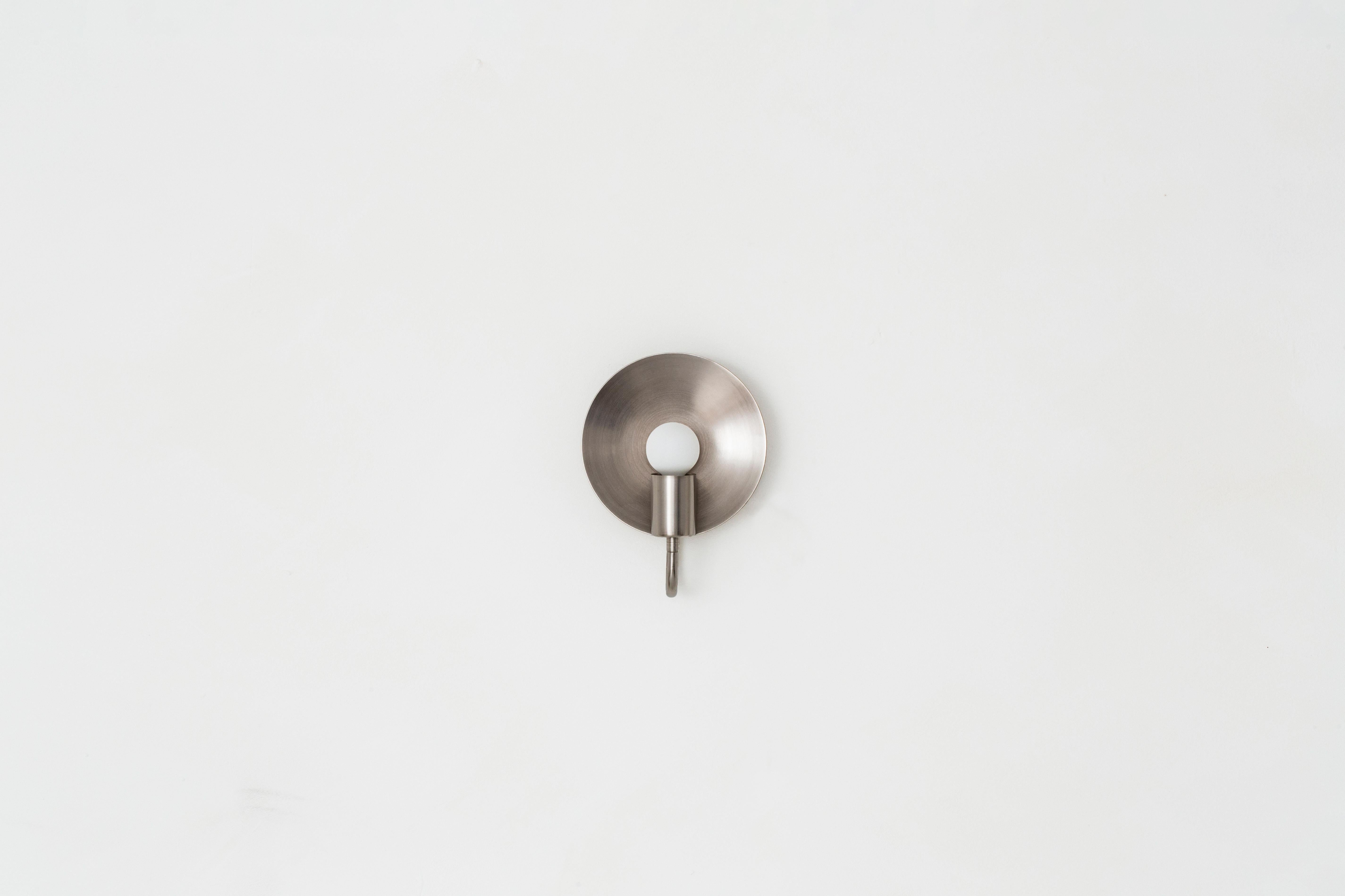 A fixed version of our Classic orbit sconce, this ADA compliant fixture is perfectly proportioned for any space where a minimal profile is desired. A modern take on an early American candle form, the piece features a radiant disc that amplifies the