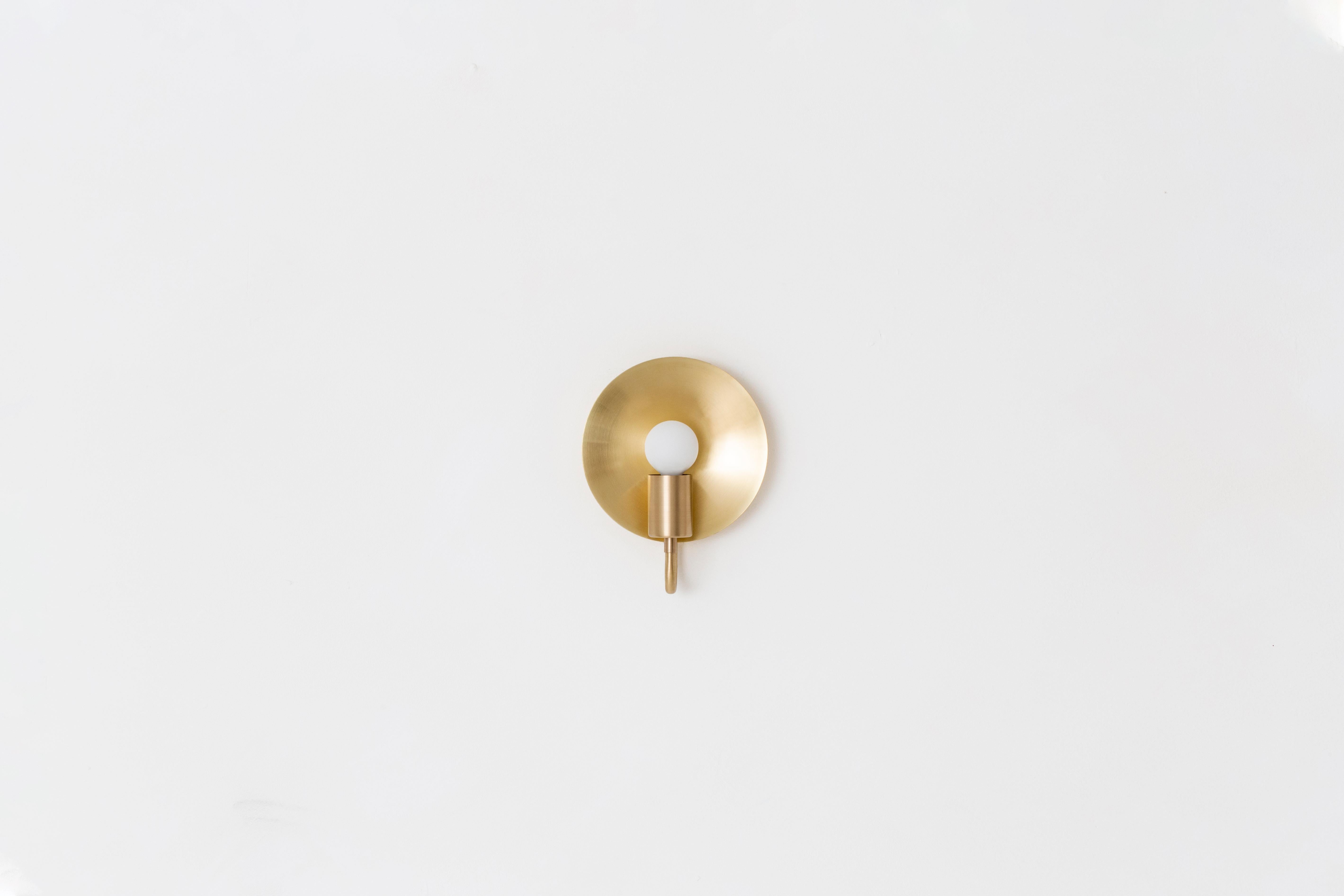 A fixed version of our classic Orbit Sconce, this ADA compliant fixture is perfectly proportioned for any space where a minimal profile is desired. A modern take on an early American candle form, the piece features a radiant disc that amplifies the