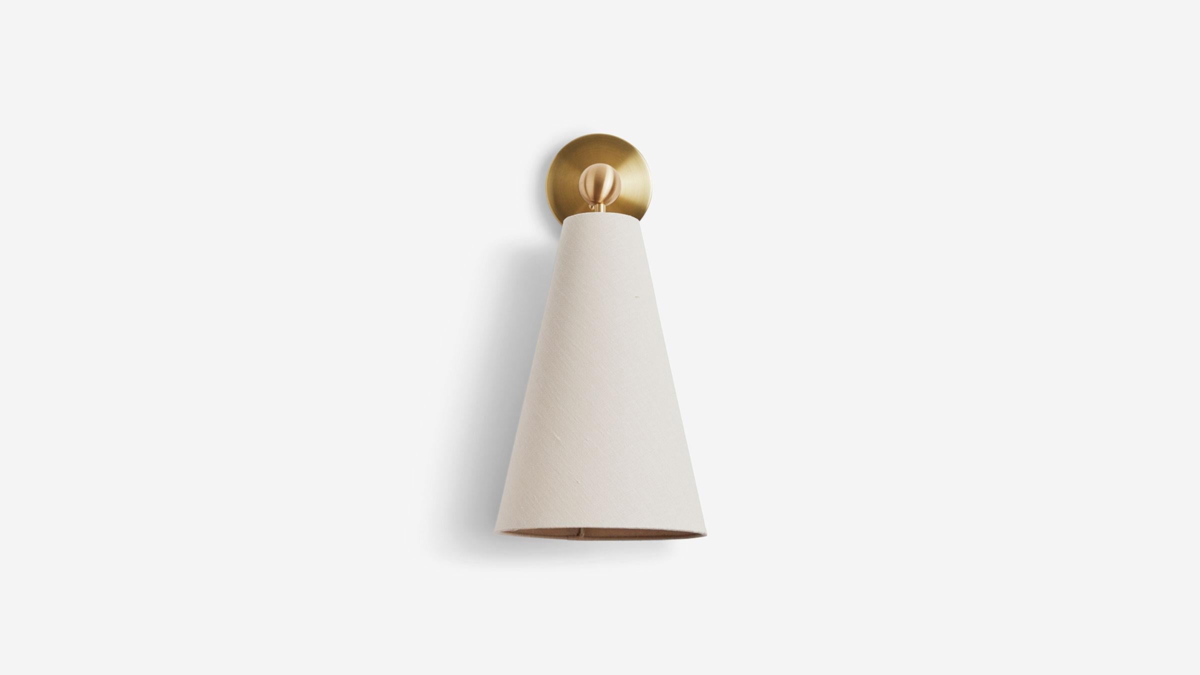 The Pendolo Sconce is composed of a directional fabric cone, radiating a subtle cast of light into a space - and a focused beam of light - in a myriad of configurations. Available in either Natural Burlap or Natural Linen, the cone form is expressed