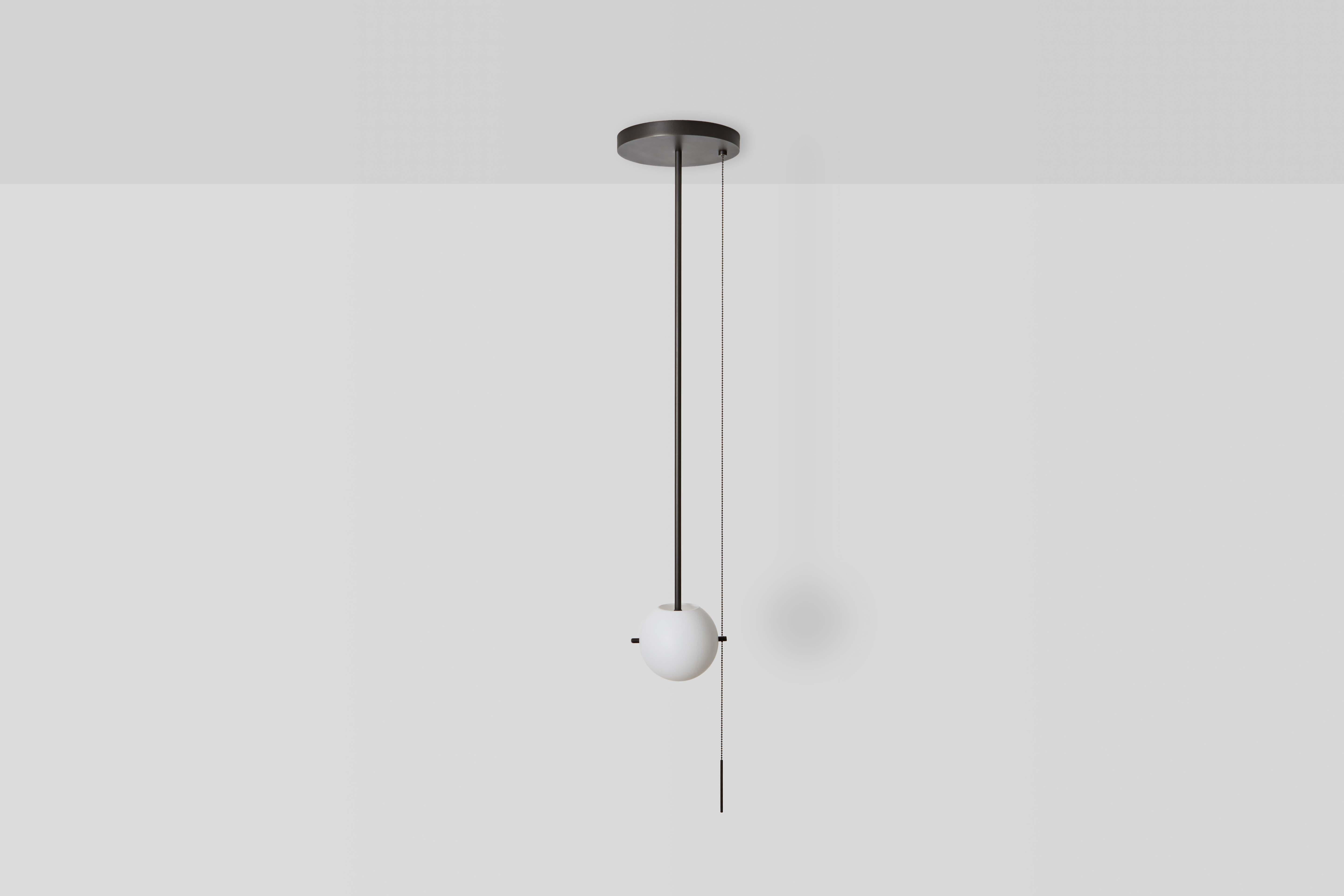 Il pendente Signal / FLUSH MOUNT è caratterizzato da un globo di vetro soffiato a mano sospeso da un baldacchino di metallo luminoso grazie a una coppia di perni metallici. Una sinuosa catena a strappo è appesantita da una sottile barra che
