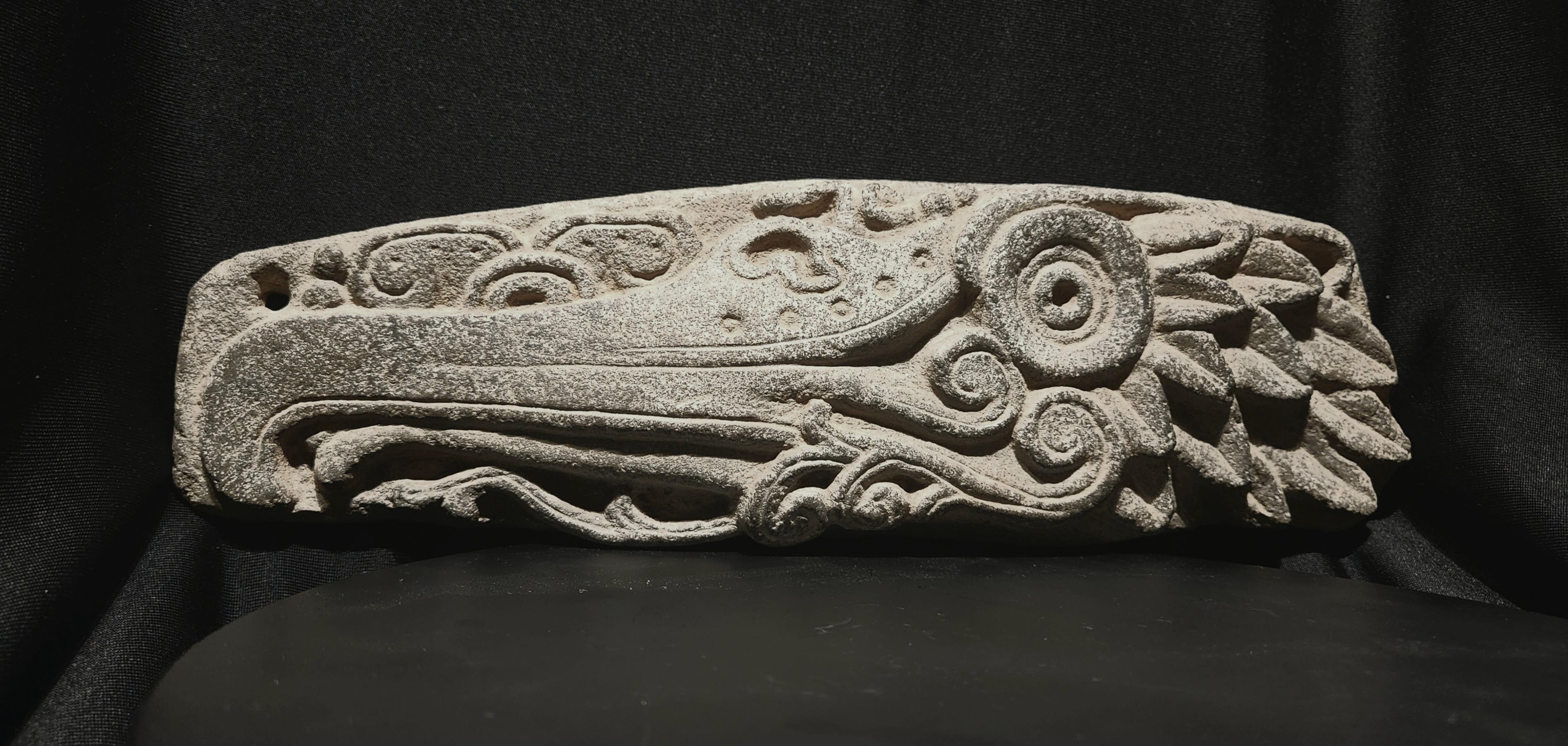 This magnificent panel is an example of the pinnacle of Maya stone carving.
It  depicts the head of a cormorant in profile, with a long hooked beak, curved tongue, large central eye, spiraling watery elements below, and deeply carved feathers on the