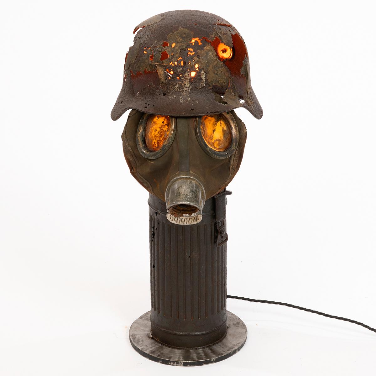 A unique table lamp comprising a German Luftwaffe steel helmet, gas mask and canister formed together to create this piece. In original condition, these historical artefacts were recovered from the Dom river area outside Stalingrad in Russia, which