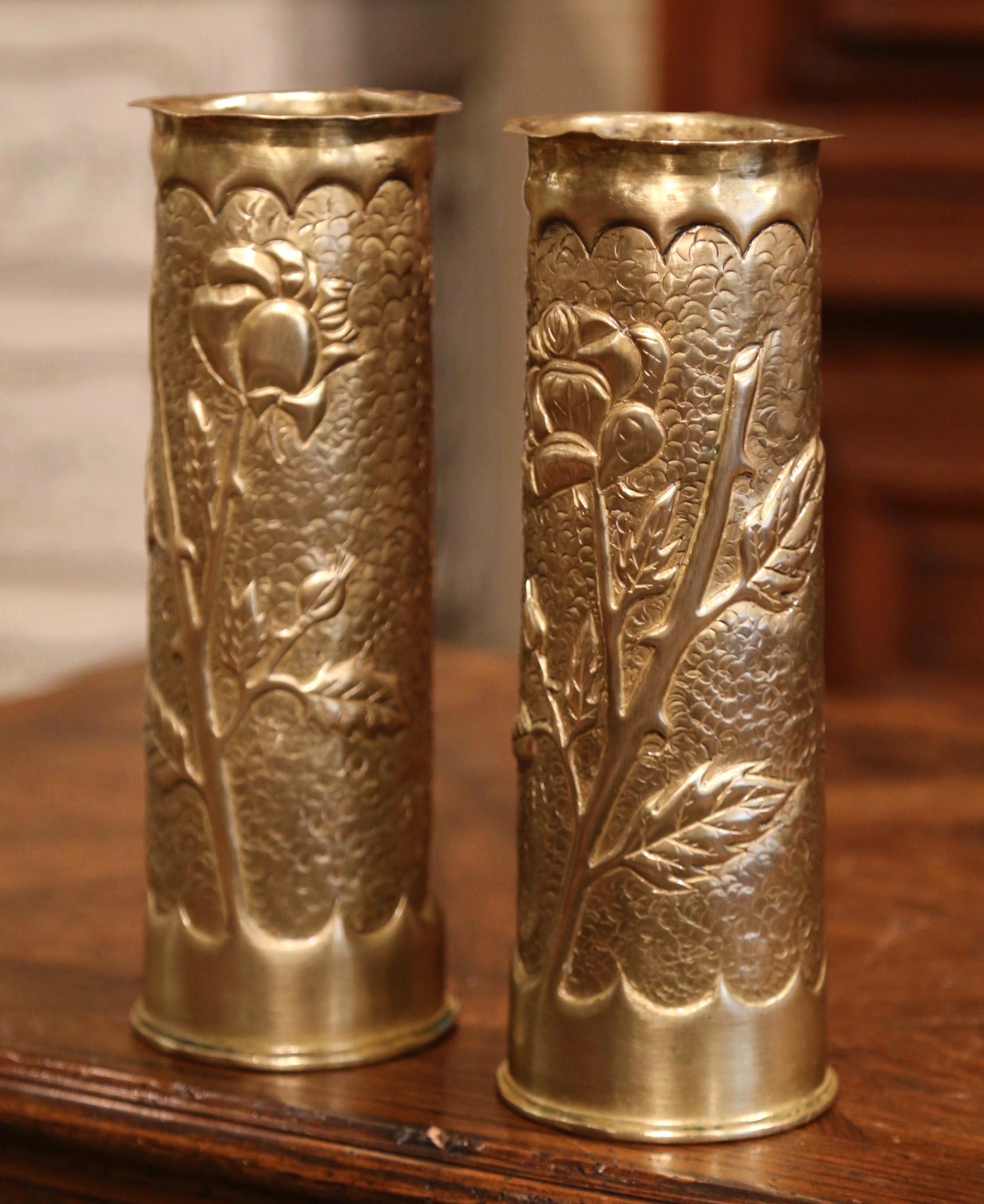 Decorate a man's office or a study display shelf with this pair of antique trench art shell vases. Made of brass and dated 1915 on the bottom, the artillery shell casing vases feature repousse floral and leaf decor. Both WWI historical memorabilia