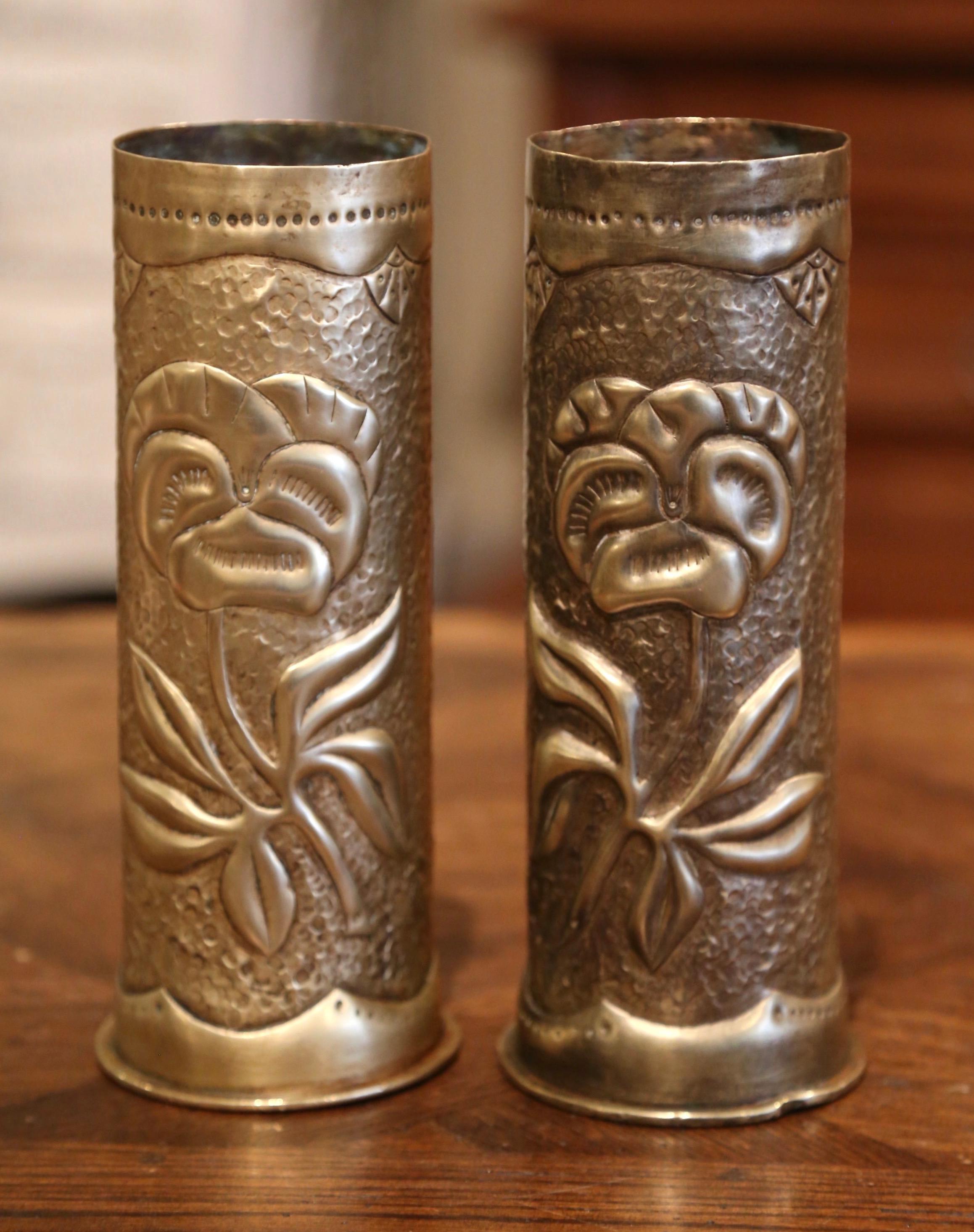 Decorate a man's office or a study display shelf with this pair of antique trench art shell vases. Made of brass and dated 1917 on the bottom, the artillery shell casing vases feature repousse floral and leaf decor. Both WWI historical memorabilia