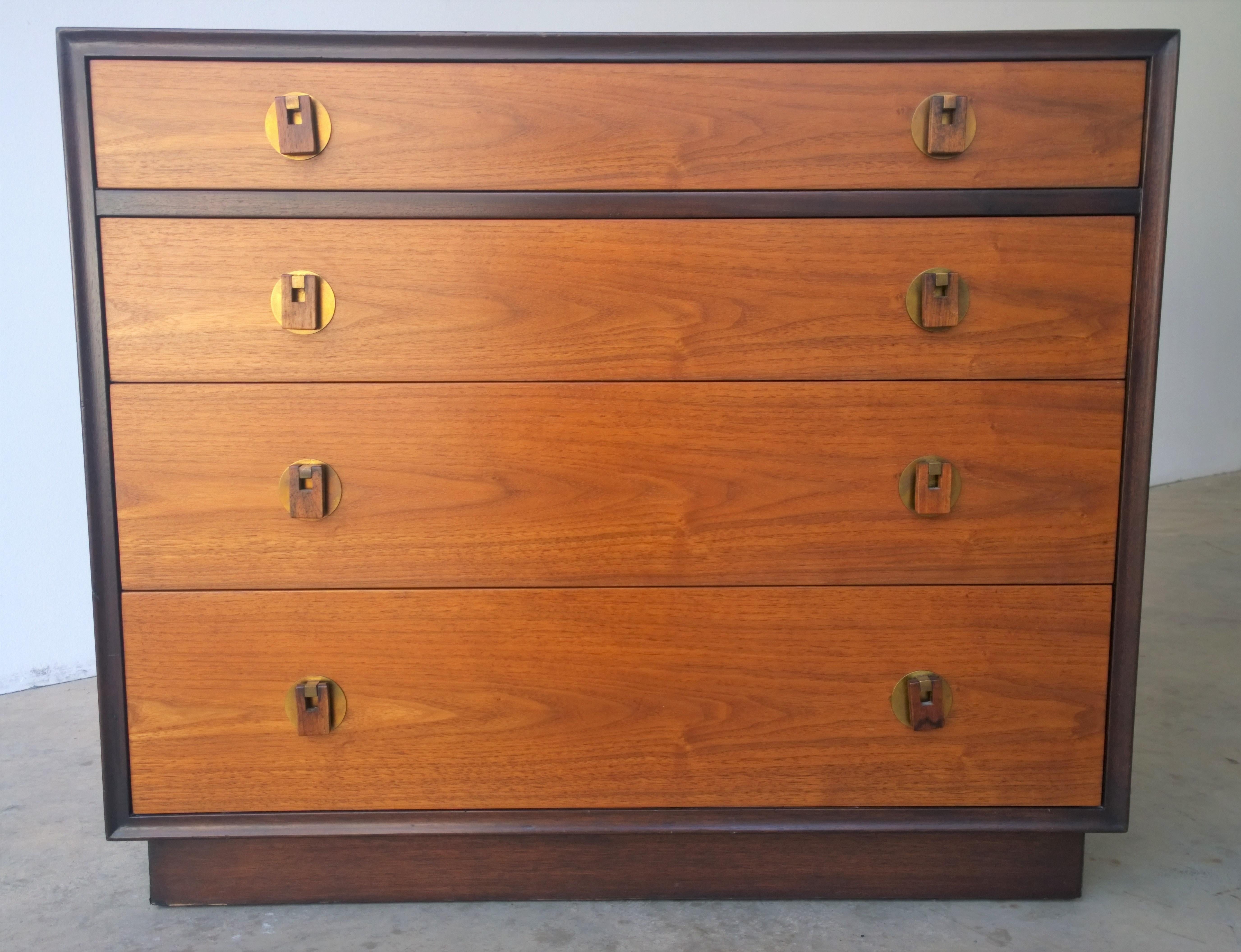 Offered is a Mid-Century Modern Edward Wormley for Dunbar black or dark brown wood frame with walnut drawers and brass pulls, chest of drawers or dresser. The offered chest of drawers was purchased at auction from the estate of Walter Hamilton