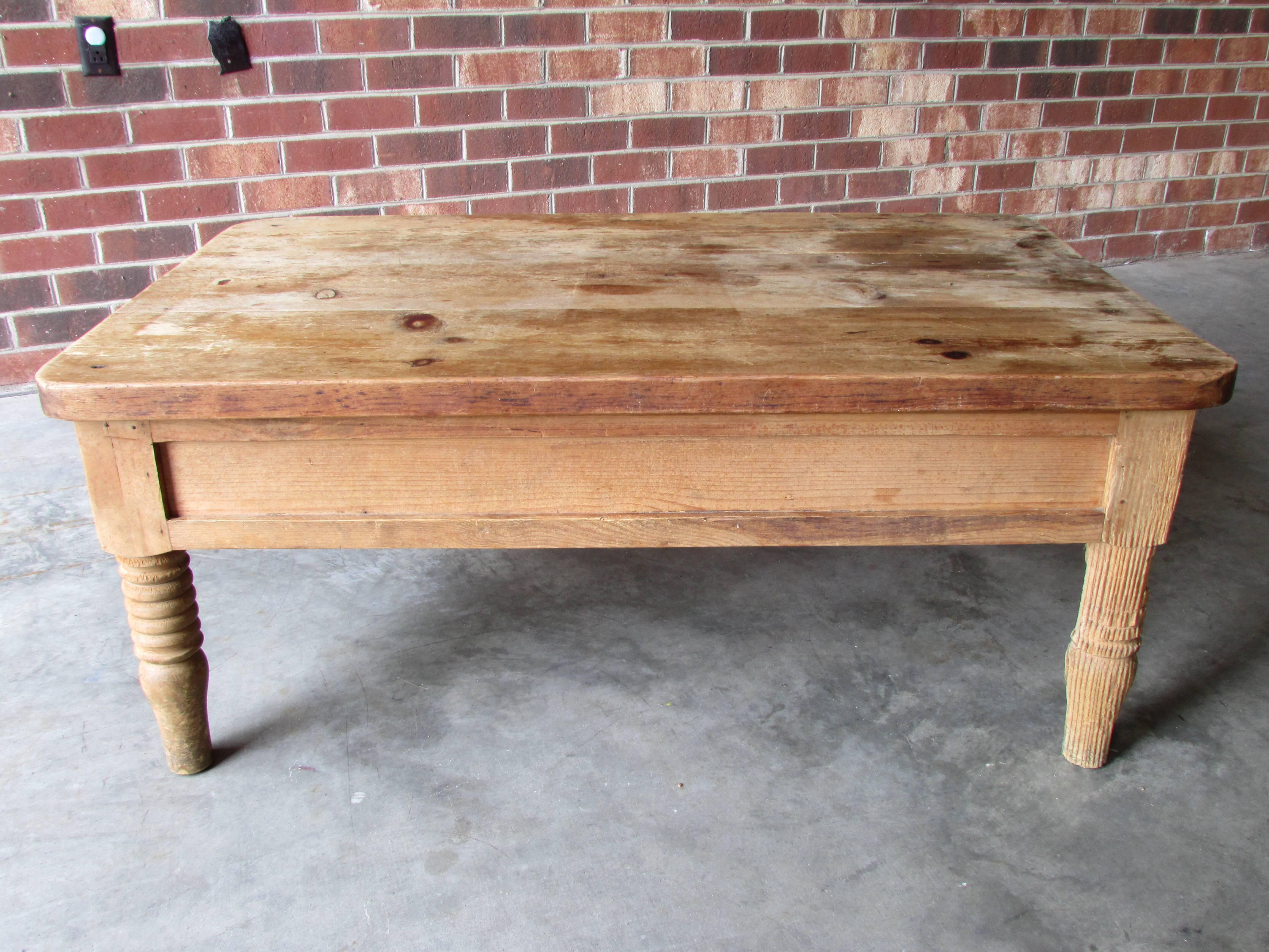 Rustic pine coffee table with a very worn and weathered finish has two drawers on either side with hand-forged iron pull handles.