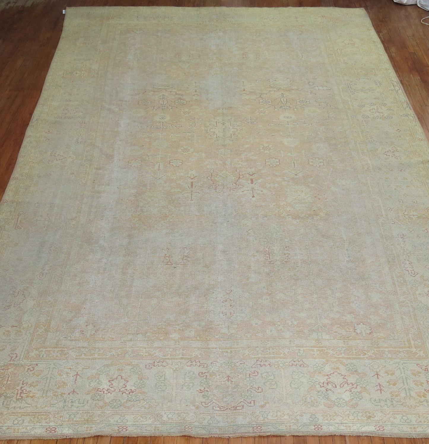 An early 20th century worn oversize antique Turkish Oushak rug in soft peach

Measures: 9'8