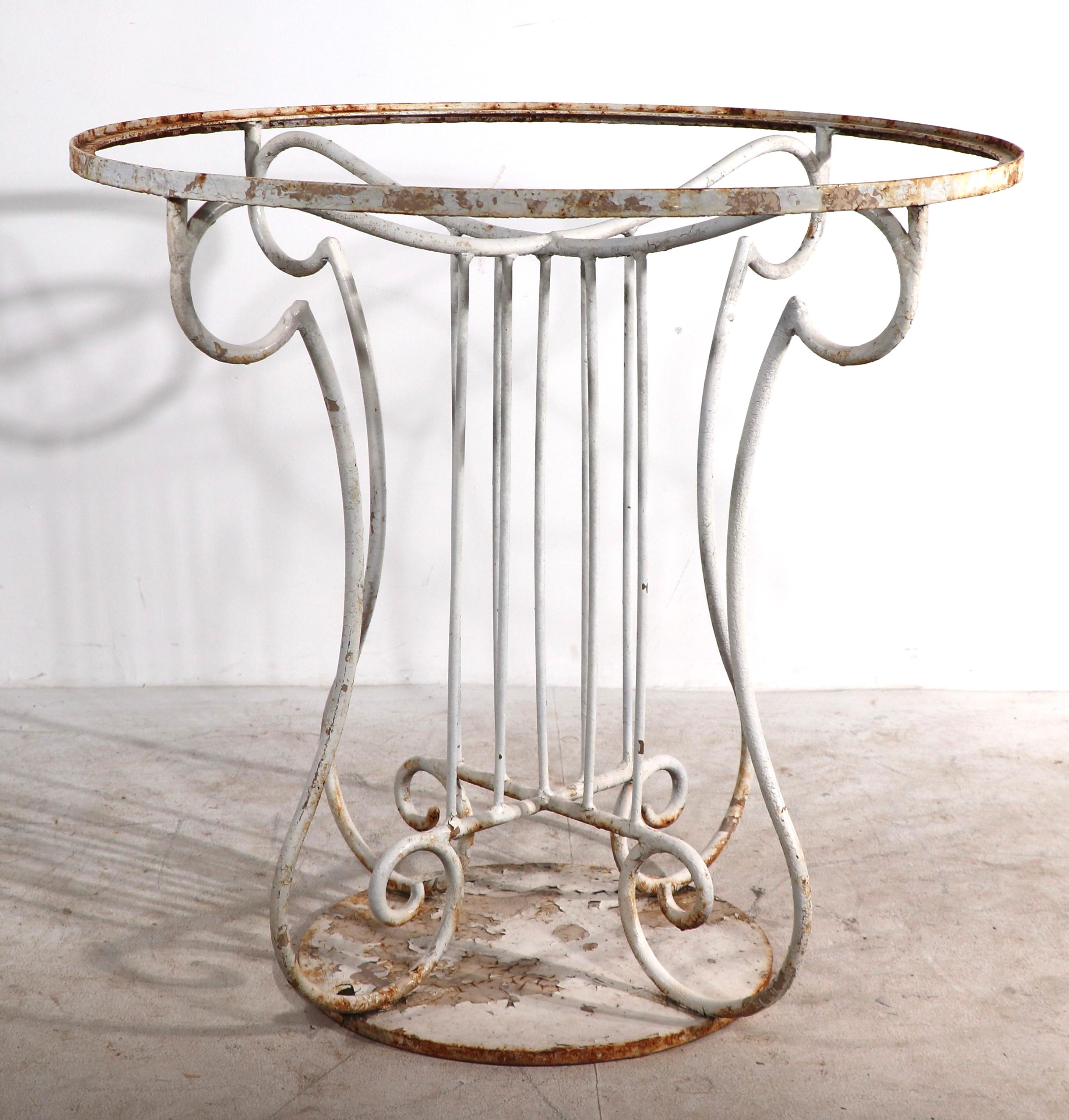 Superb wrought iron table base with stylized center, on heavy solid iron disk foot base. The center post is reminiscent of a classical column, it supports a round top ( 30 in. dia. ) which has a rim to accept a plate glass top ( glass not included