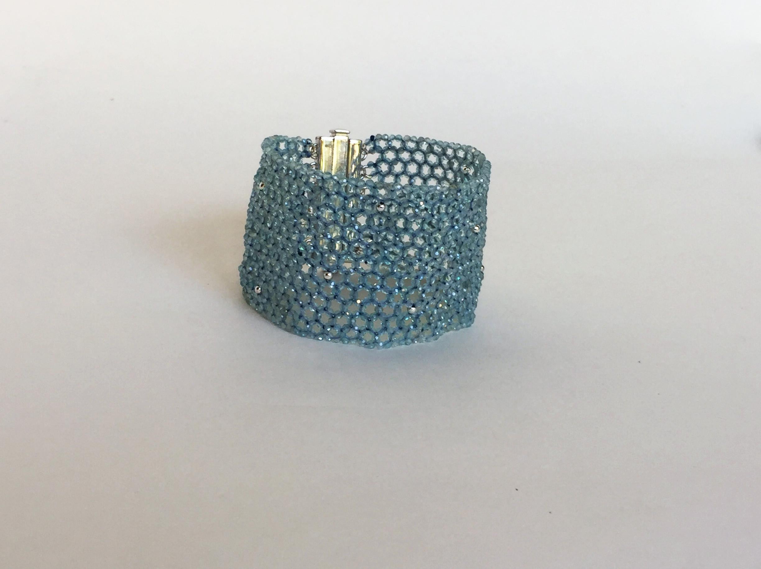 This woven aquamarine and 14k white gold cuff bracelet with sterling silver clasp elegantly drape the wrist like sparkling lace. The faceted baby blue aquamarine and 14k white gold beads are woven into a 1.5-inch wide cuff bracelet. At 6.8 inches