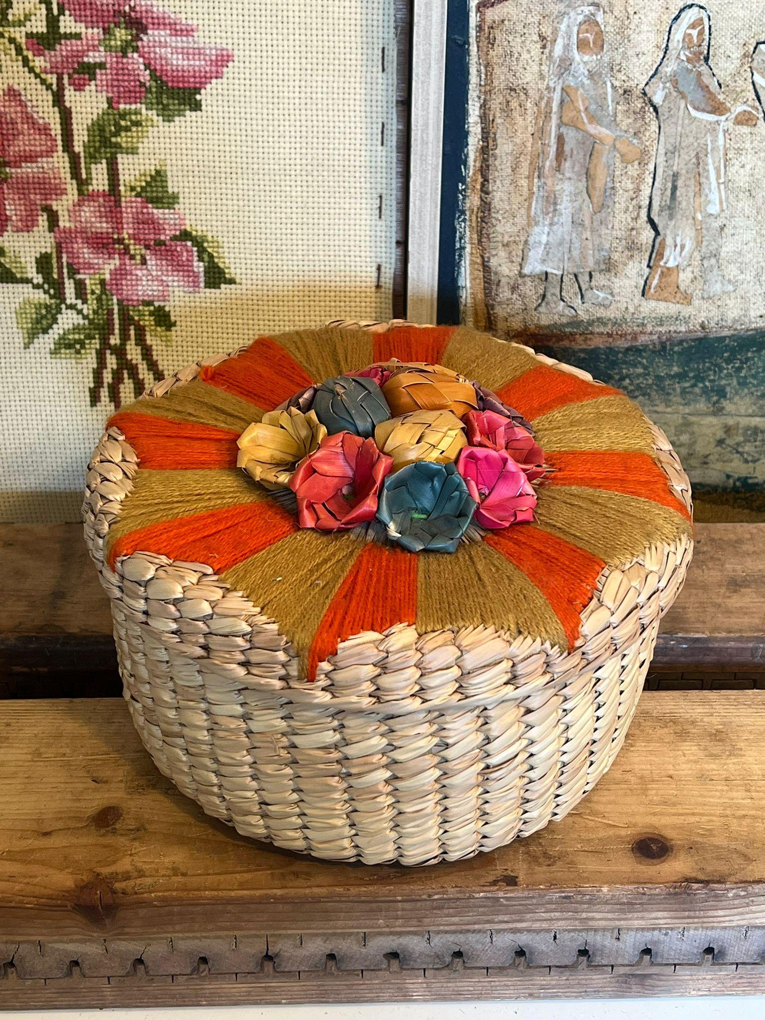 Questo pezzo è probabilmente una cappelliera d'epoca, che potrebbe essere un eccellente cesto d'arredamento e/o un ottimo contenitore rotondo. È ornato da fili intrecciati e da fiori di paglia. Questo pezzo ha una bella patina e carattere.