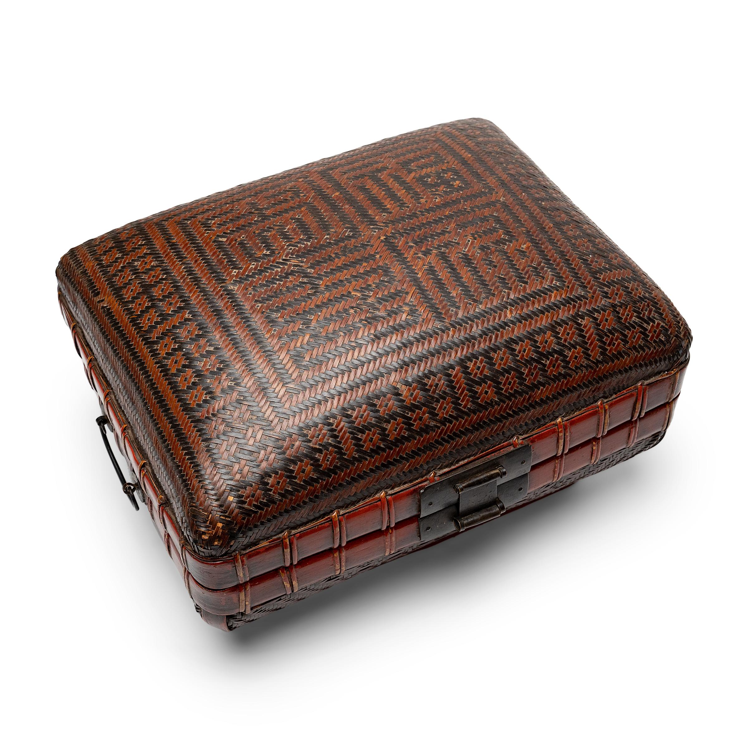 This cushion-form box of woven reed and lacquered bamboo dates to the early 20th century and is a lovely example of Chinese basketry. The box is woven of reed strips darkened with black and burgundy-red lacquer, forming a design of four auspicious