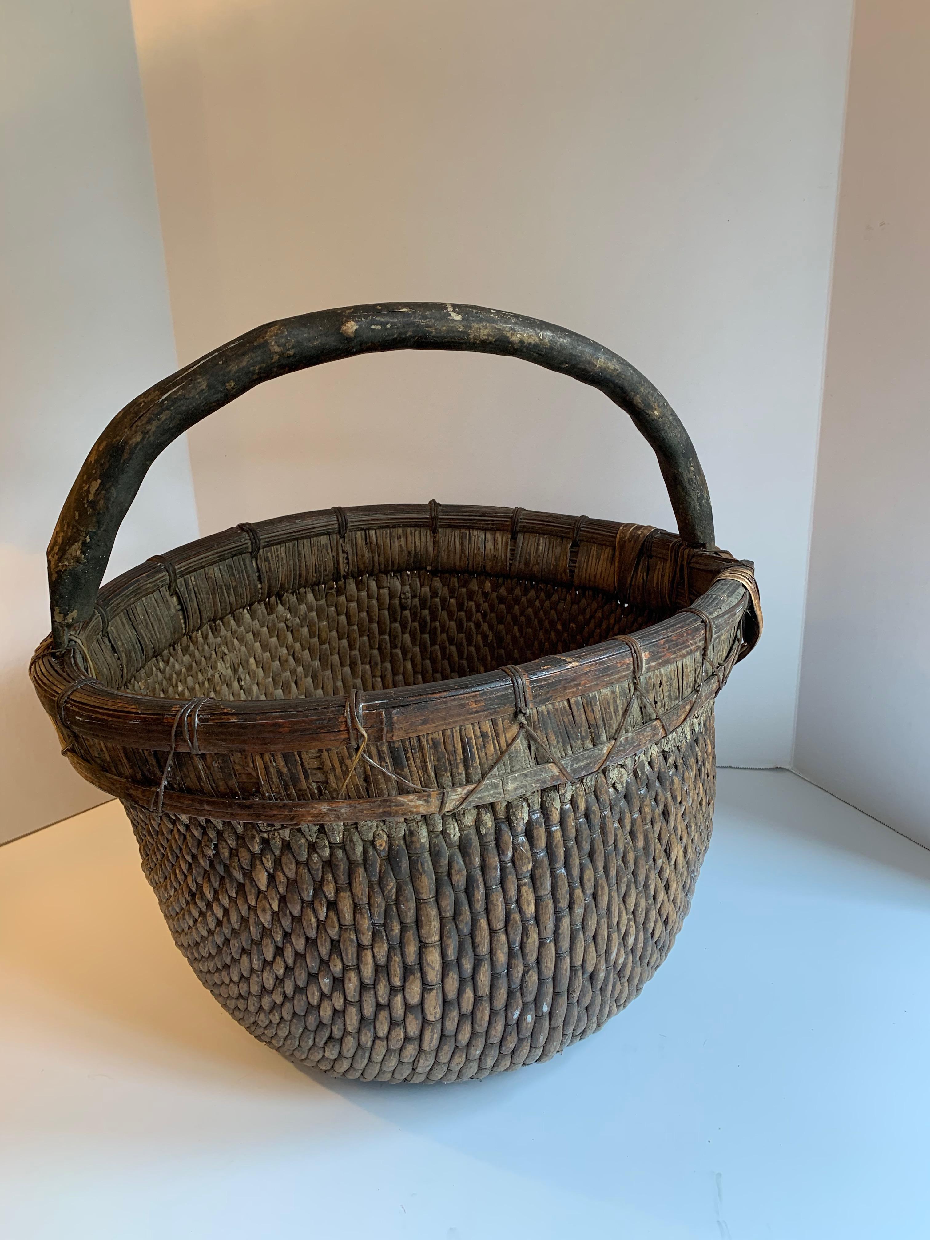 Woven willow basket with handle - A wonderfully aged and patinated woven basket. Sturdy and impressive enough to use for laundry, holding firewood, magazines, centerpieces or even a decorative holder for a potted plant. Any age, scratches nicks add