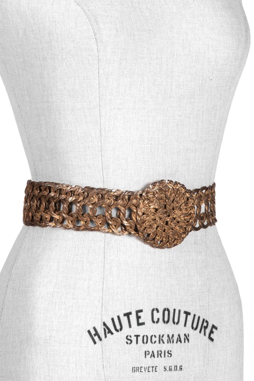 Unique c. 1970s woven metal thread belt with metal disk buckle.

The alluring artisanal belt features a round metal disk buckle covered with woven patinized silvery gold tone metal threads. The buckle is set on a smooth metal wire belt that is made