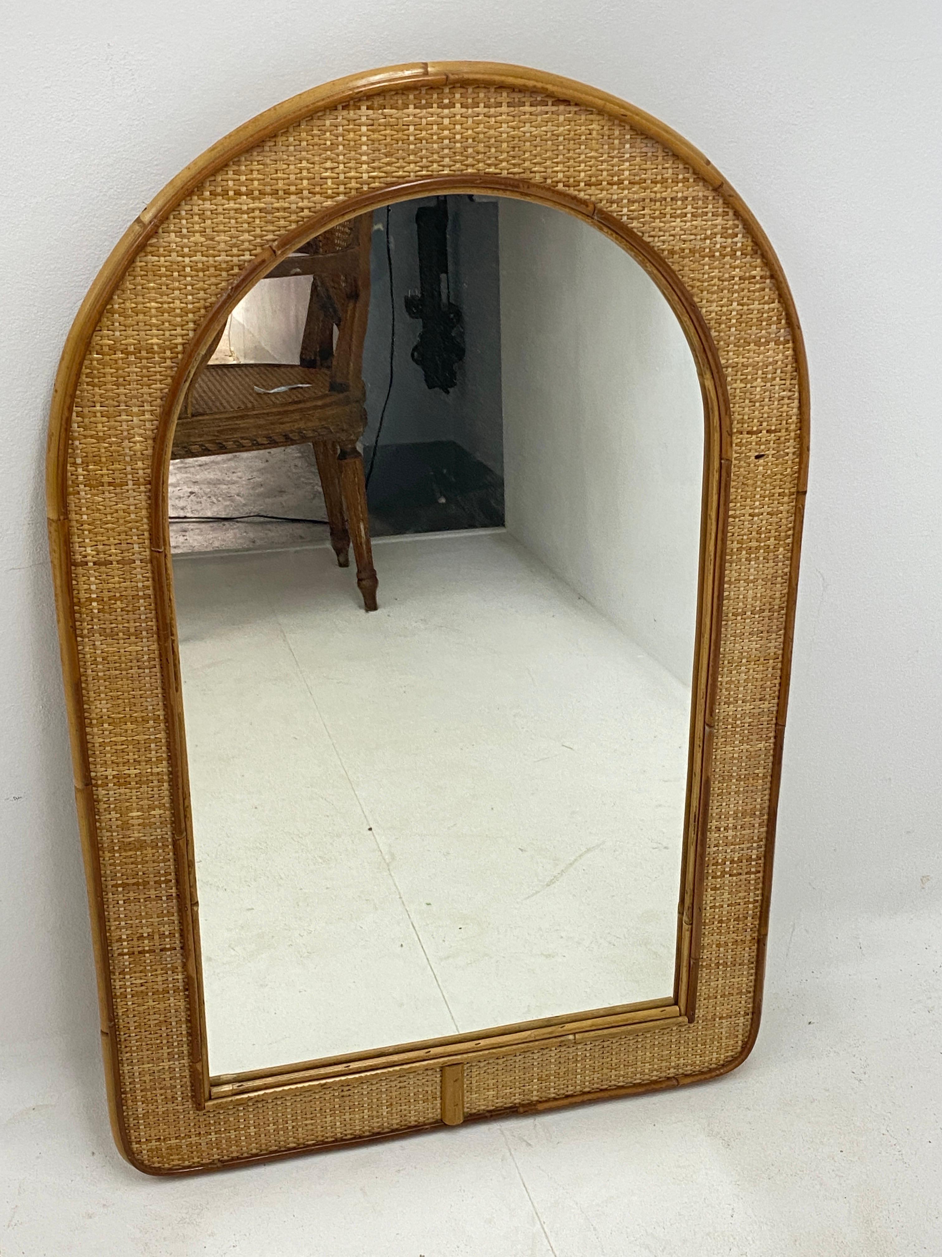 This is a bamboo and rattan mirror. Made in Italy circa 1970. The color is brown.
Midcentury wall mirror features a veneer of parquetry in a herringbone pattern and faux bamboo detailing. Good condition with only very minor imperfections consistent