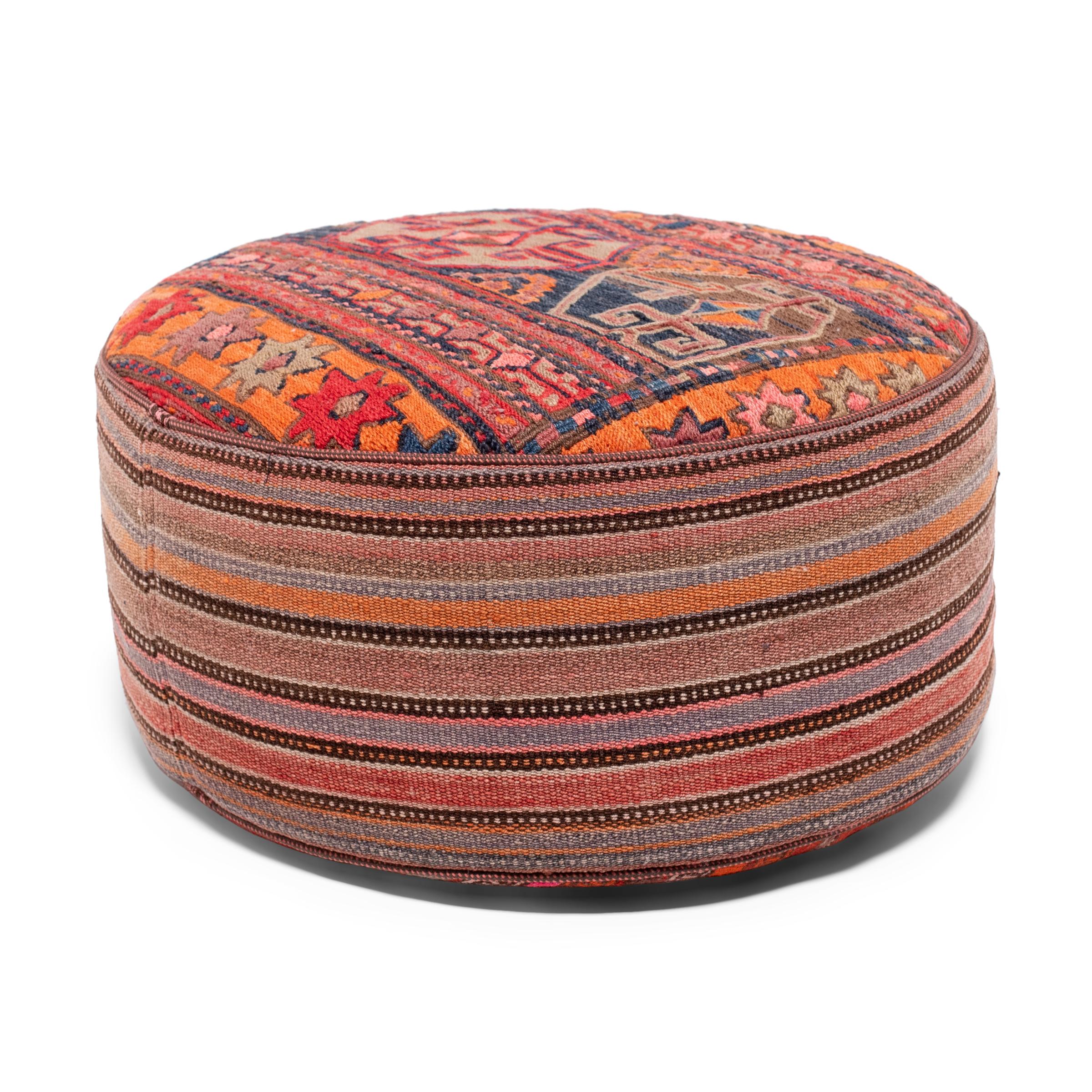 This vintage woven ottoman brightens its surroundings with the upbeat colors and patterns of Turkish kilim tapestry. The cylindrical pouf is upholstered in a colorful wool textile woven with stripes and traditional geometric motifs in a palette of
