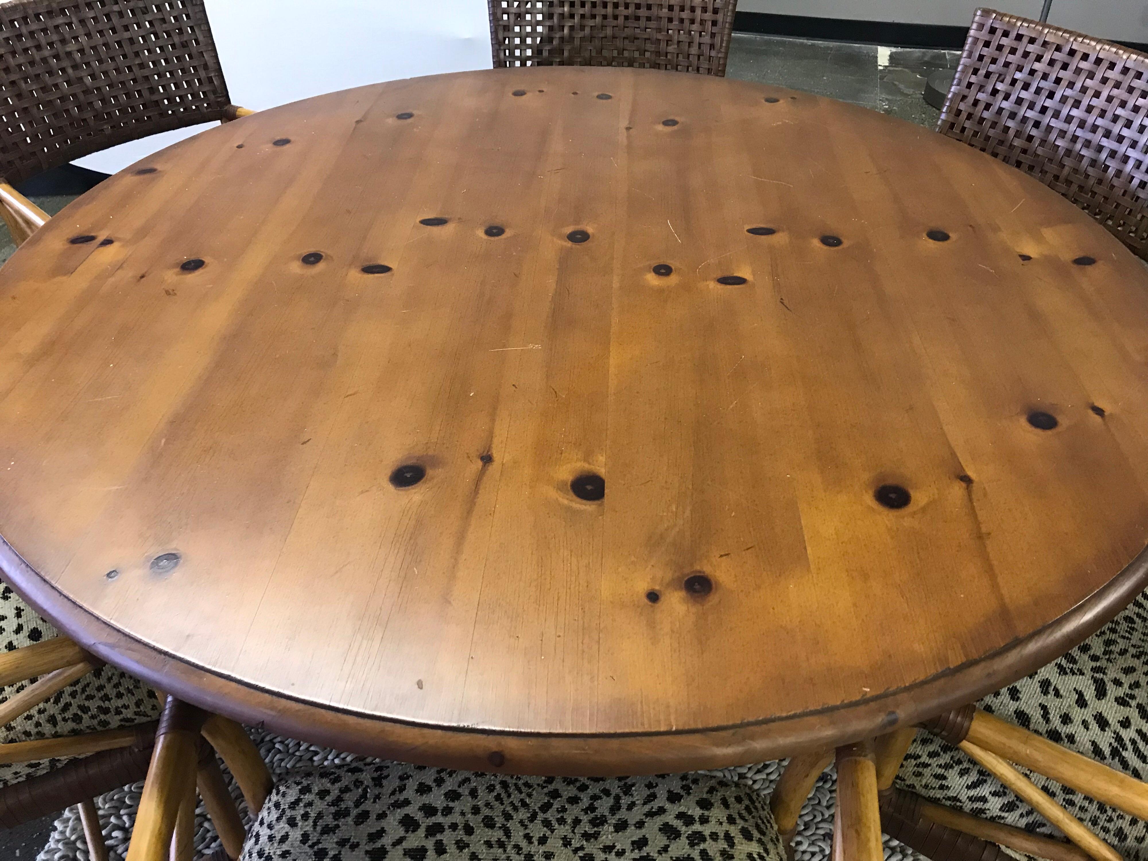 This casual Hickory White dining set includes a round table and six matching chairs. Chairs feature woven leather, bamboo and leopard seat fabric and are in mint condition. The round pine table top rests on a distressed black wood base and is five
