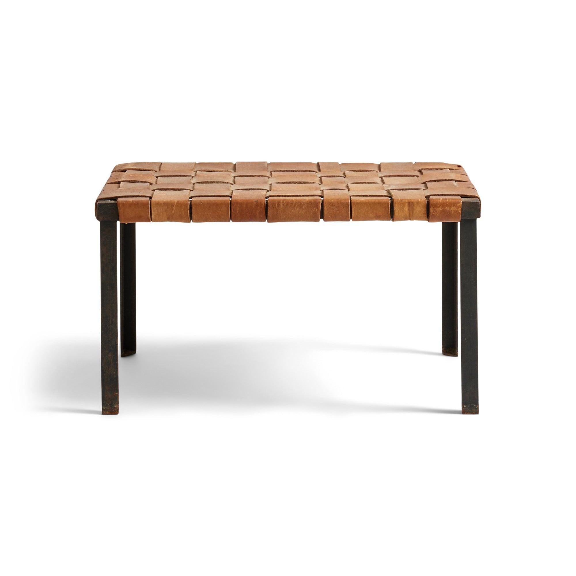 Ein warmer und eleganter, handgefertigter vierbeiniger Hocker  aus Schmiedeeisen unter Beibehaltung des ursprünglichen dicken gewebten Butterscotch-Lederbandes.
