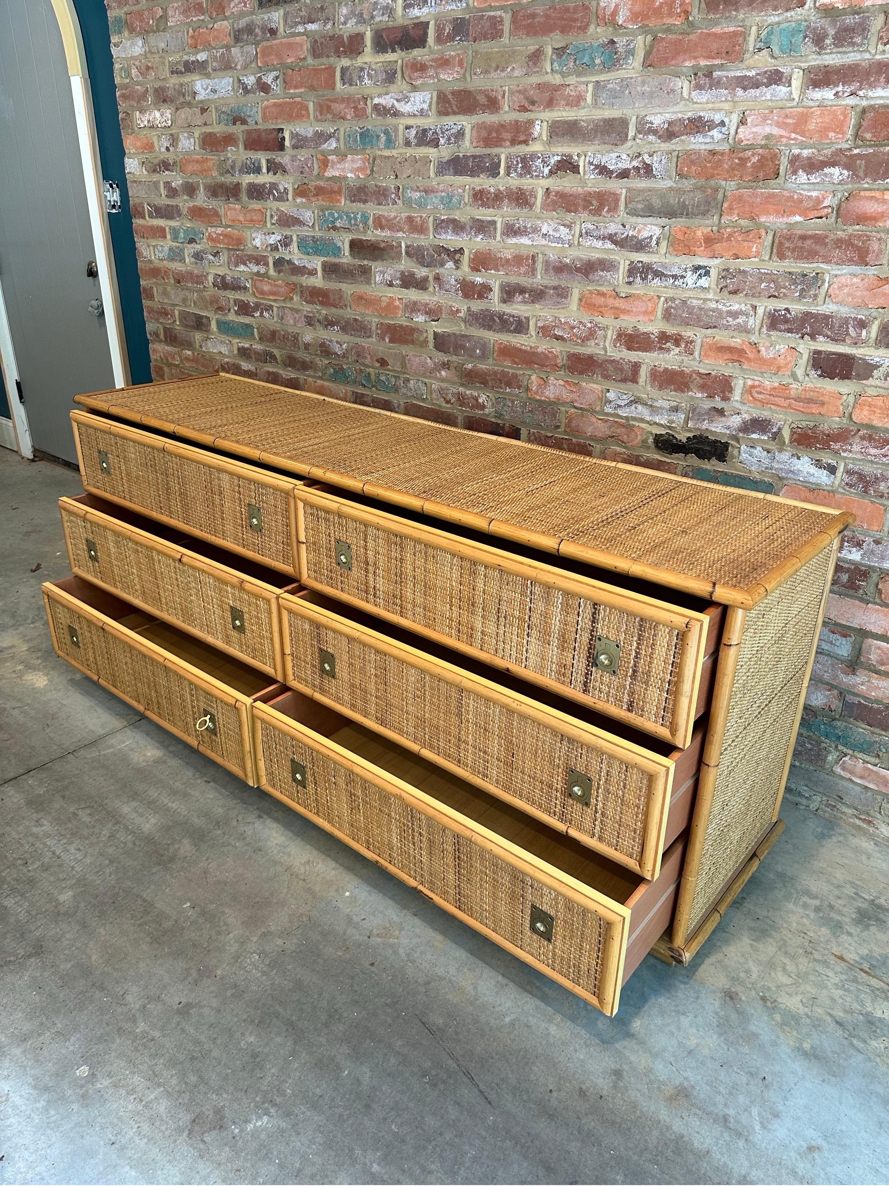 This dresser is a beautiful piece from the 1970s, crafted by the renowned Italian brand Dal Vera. It showcases a combination of bamboo and woven rattan, materials that were popular for their natural aesthetic and durability. The brass fittings add a