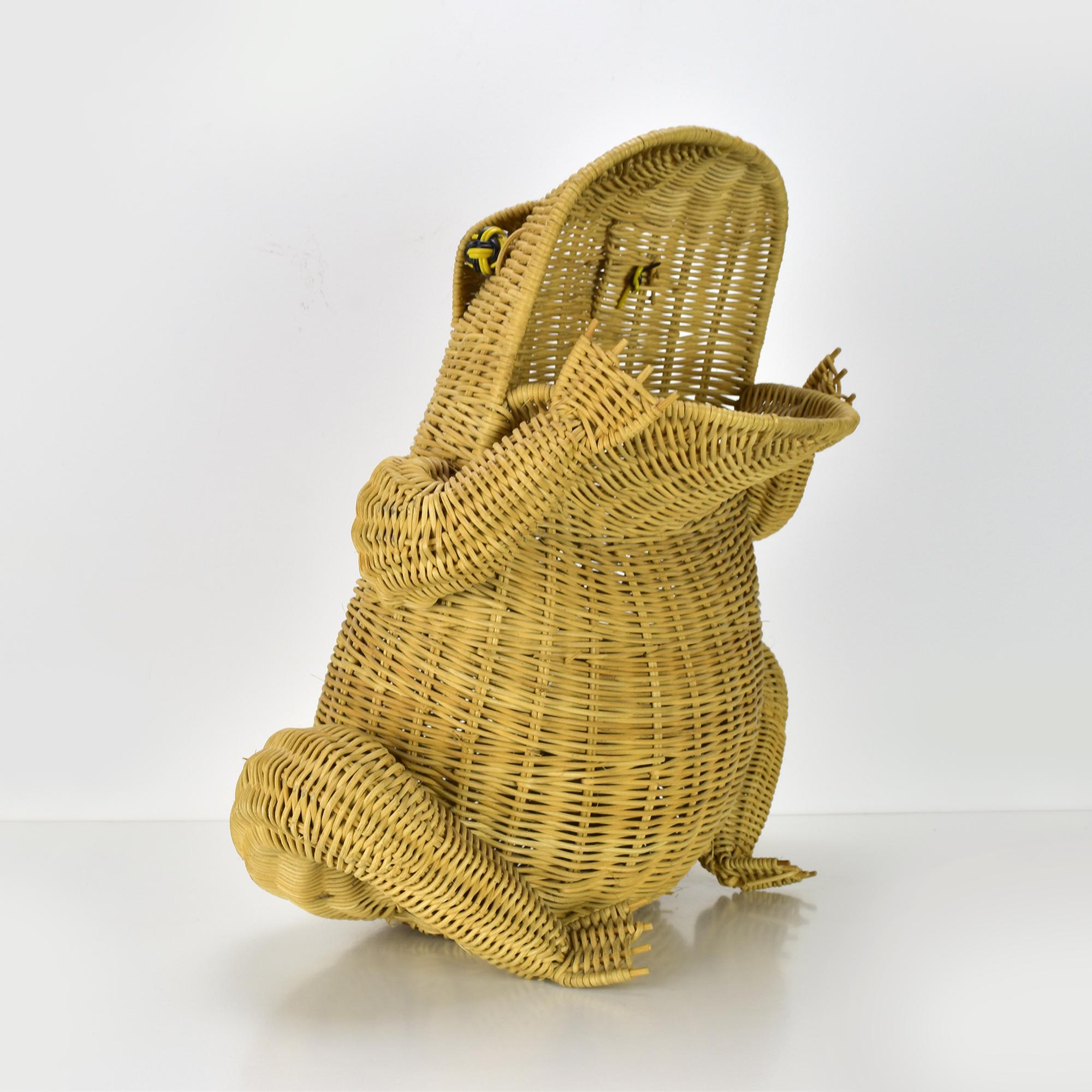 Questo esclusivo cestino in rattan intrecciato a forma di rana funge da affascinante portariviste e dona un tocco giocoso e stravagante a qualsiasi spazio. Realizzata con un'intricata lavorazione del vimini, questa rana si ispira allo stile di Mario