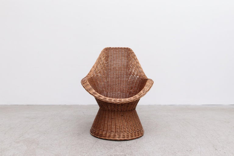 Woven Rattan Peacock style lounge chair with built-in arm rests and round base. In original condition, with minimal wear and rattan loss. Wear is consistent with its age and use.