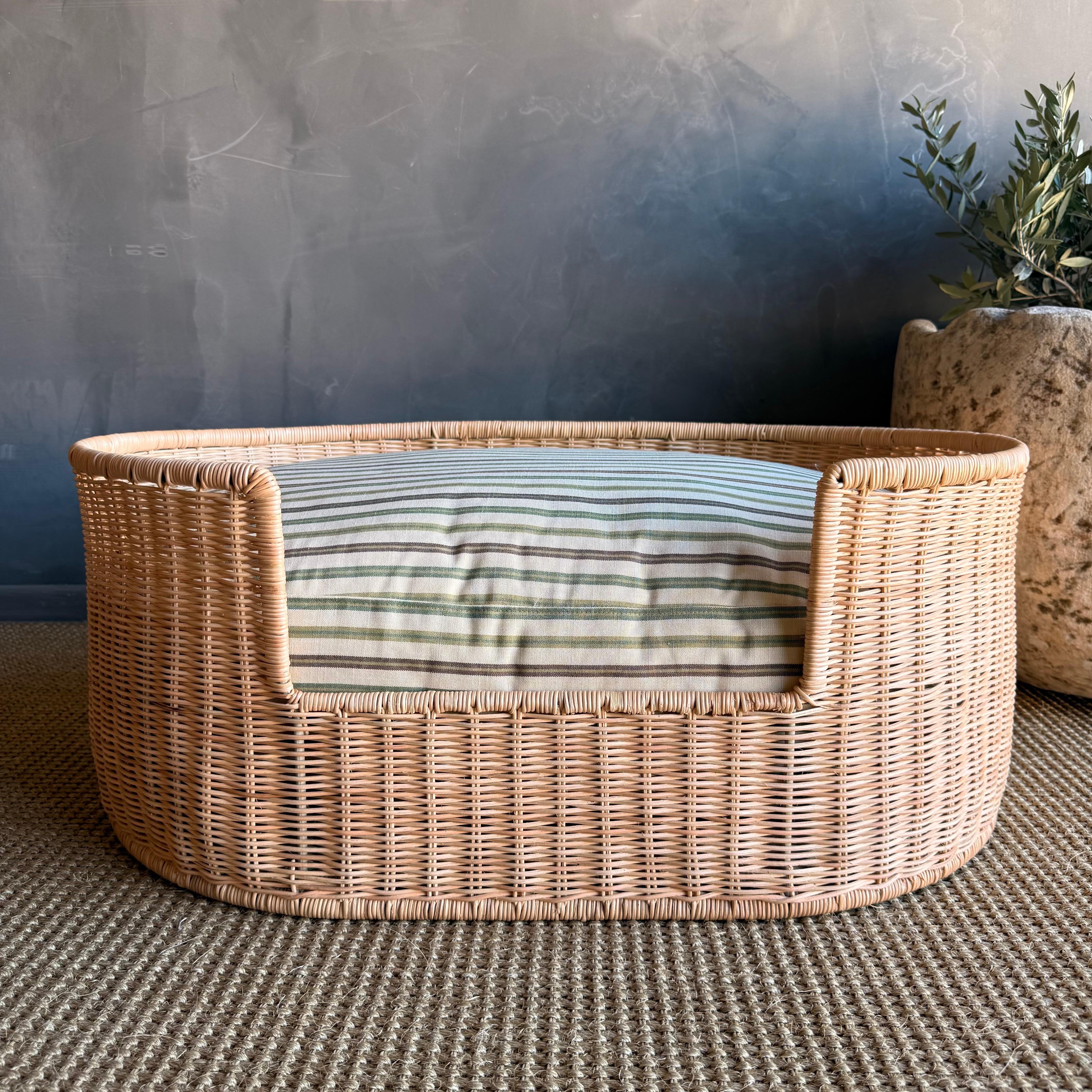 A cozy retreat for furry friends, it showcases a handwoven rattan frame with a dipped front for easy access. The plush cushion, adorned with a delightful stripe, made from outdoor material that can be washed easily.  There is a zipper to remove the