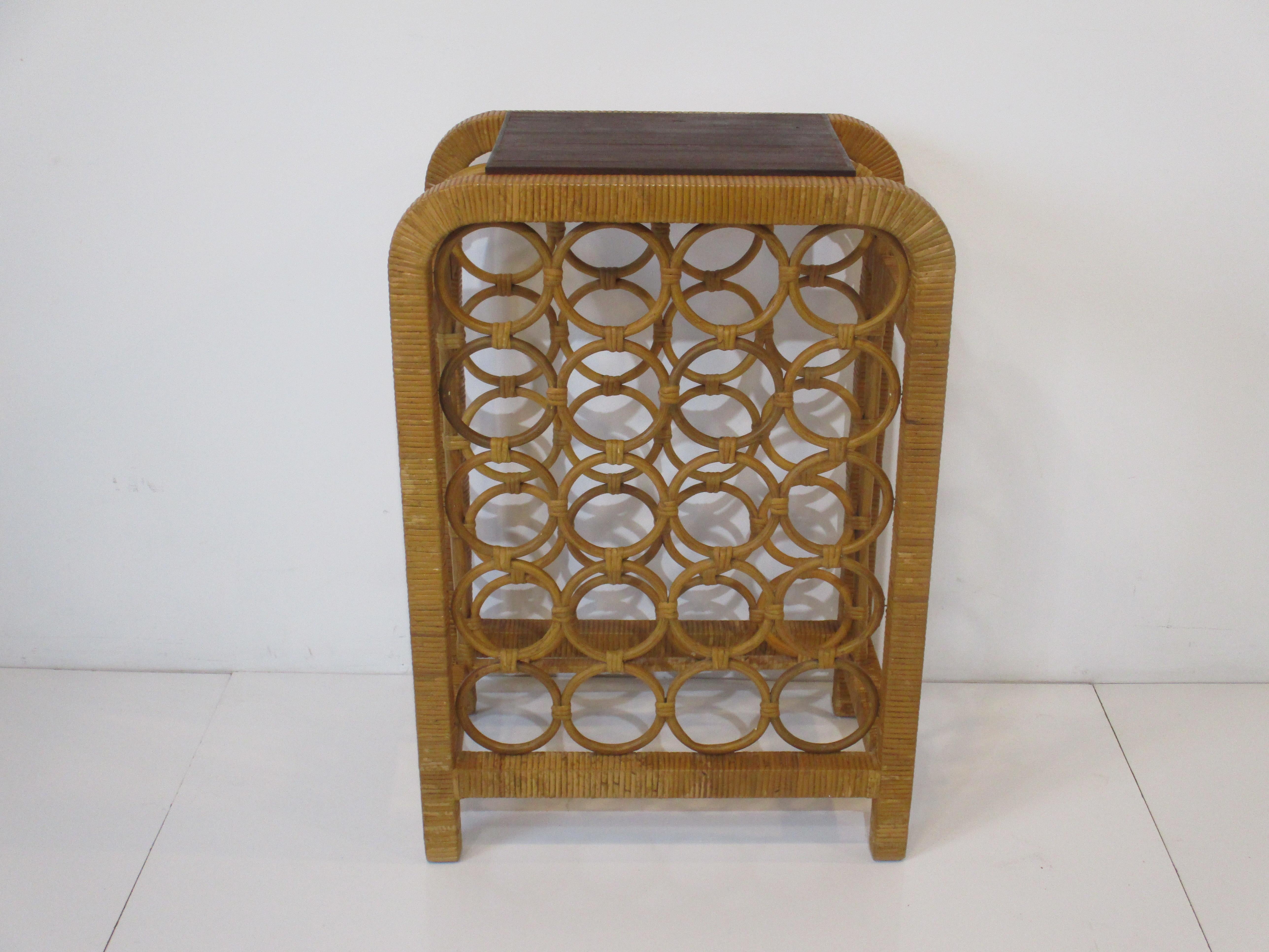 A woven rattan wine / bar rack with twenty spaces for wine or liquor bottles and topped with a dark butcher block serving area. Sized perfectly for a wall or corner area where space is a concern.