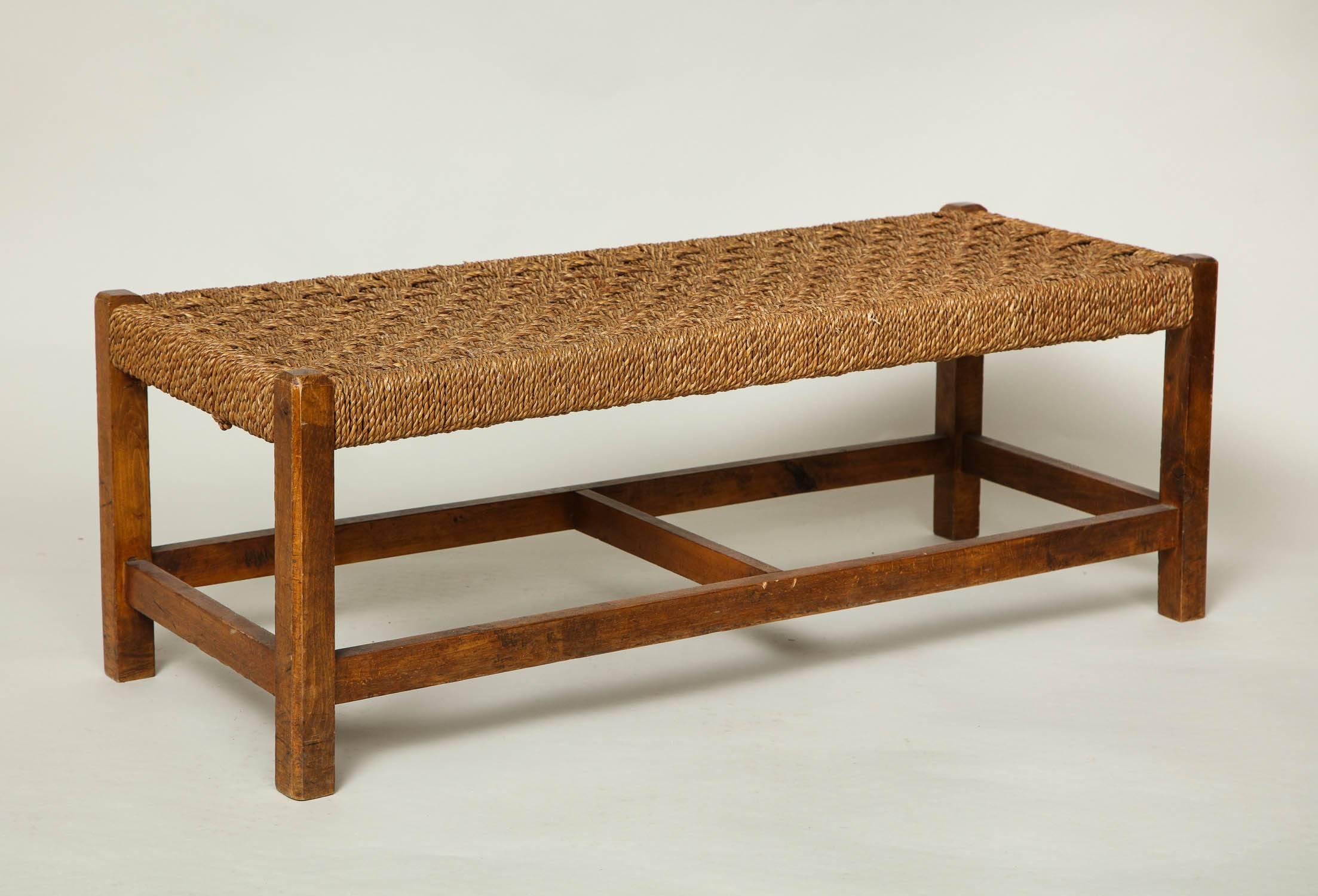 A rectangular oak luggage stool with square chamfered legs joined by stretchers and a deep woven hemp rope top, England, circa 1910. Small and handy for setting luggage on.