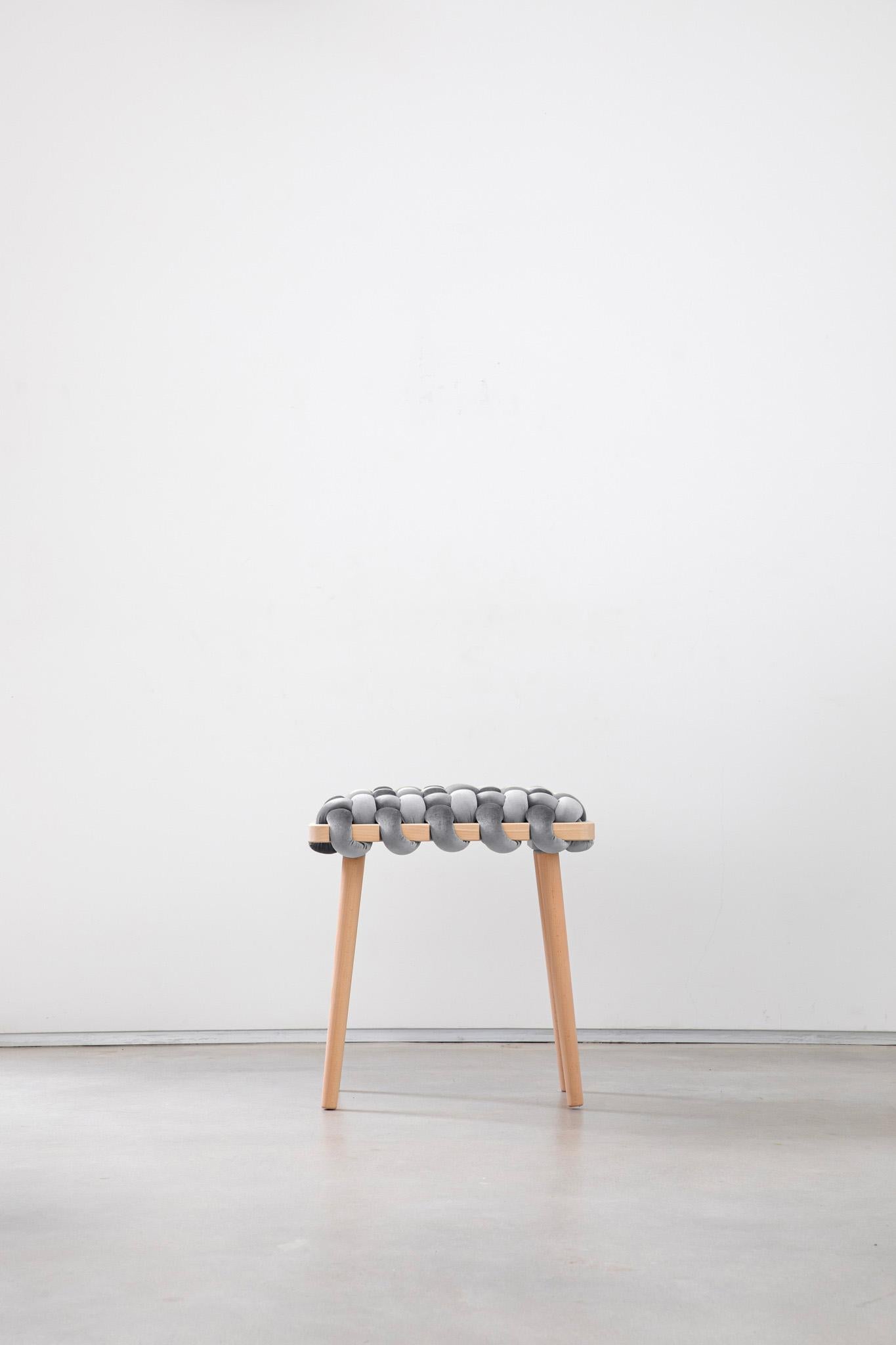 Expertly crafted with a blend of fine velvet fabric and natural Beechwood, the hand-woven stool enhances any entryway or living space with its elegant and playful design. This lasting piece combines beauty and functionality, creating a stunning
