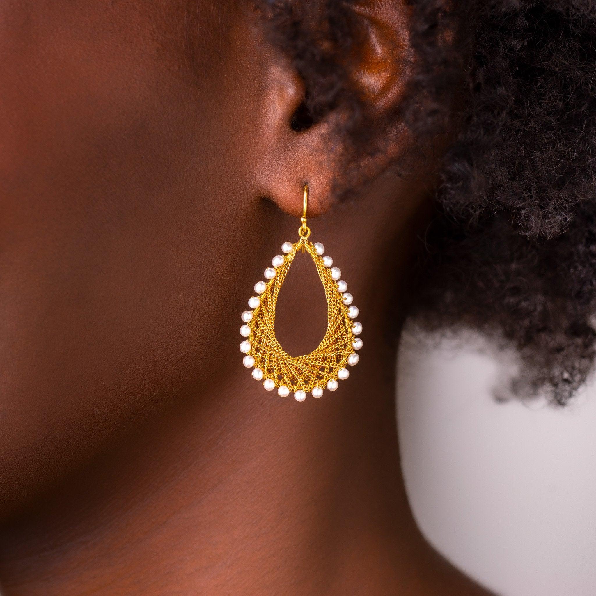 These distinctive earrings feature festoons of gold chain delicately woven into a shimmering web adorned with creamy Pearls. The smooth surface of the Pearls emanates a lustrous glow, like dewdrops in moonlight. The effect is subtle, sensual, and