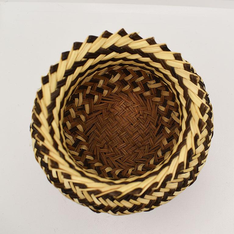 A small woven basket shaped like a vase. Woven with natural fibers in geometric patterns, this small decorative piece of folk art would be beautiful on a nightstand or coffee table. 

Dimensions:
4.5