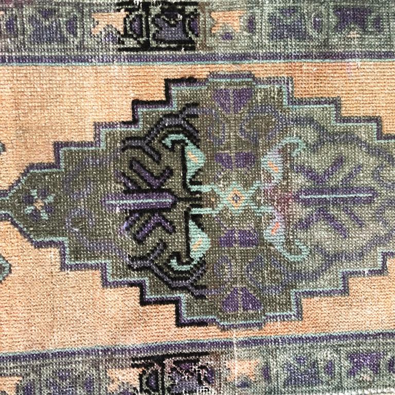 Peach and purple woven wool rug from Turkey. Featuring beautiful purple and peach tones and a geometric tribal pattern in the middle. Great for a hallway, beside a bed, in a foyer or kitchen. This would also be an excellent piece for use in making a