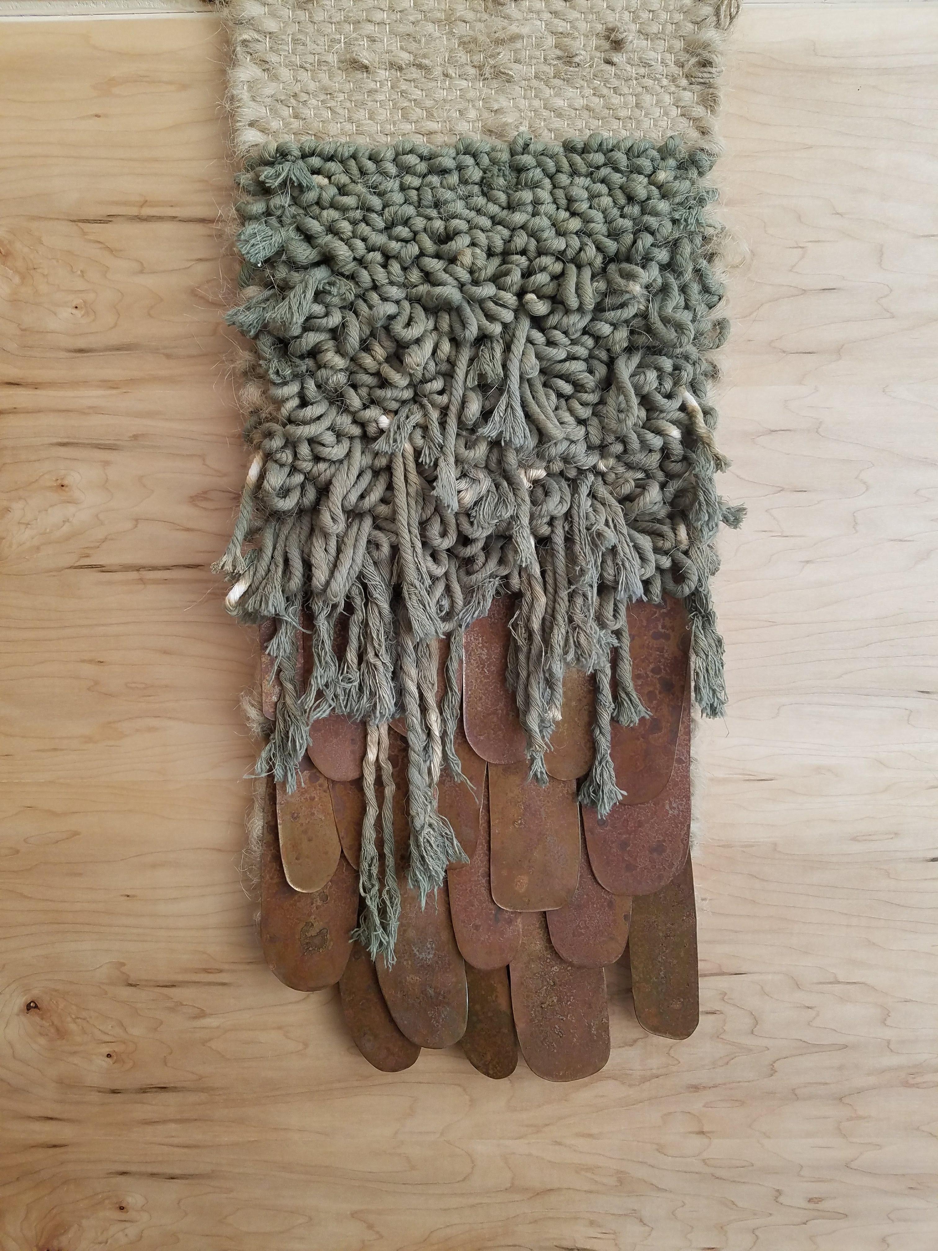 Handwoven, tapestry style, wall hanging by Janelle Pietrzak of All Roads. Rustic hemp fiber is paired with hand dyed army green cotton yarn. Hand cut steel shapes are treated with a special patina for a rusty finish and hand waxed. Weaving hangs
