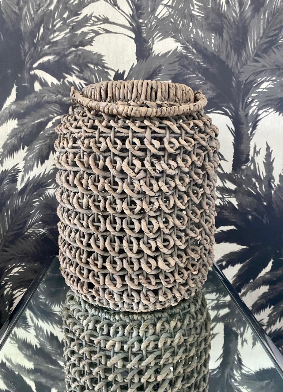 Organic Modern woven seagrass floor lantern. Handcrafted of water hyacinth with beautiful large woven loops. The basket lantern has a woven rattan base and is fitted with central ledge which holds a large glass votive vase for candles.
Beautiful