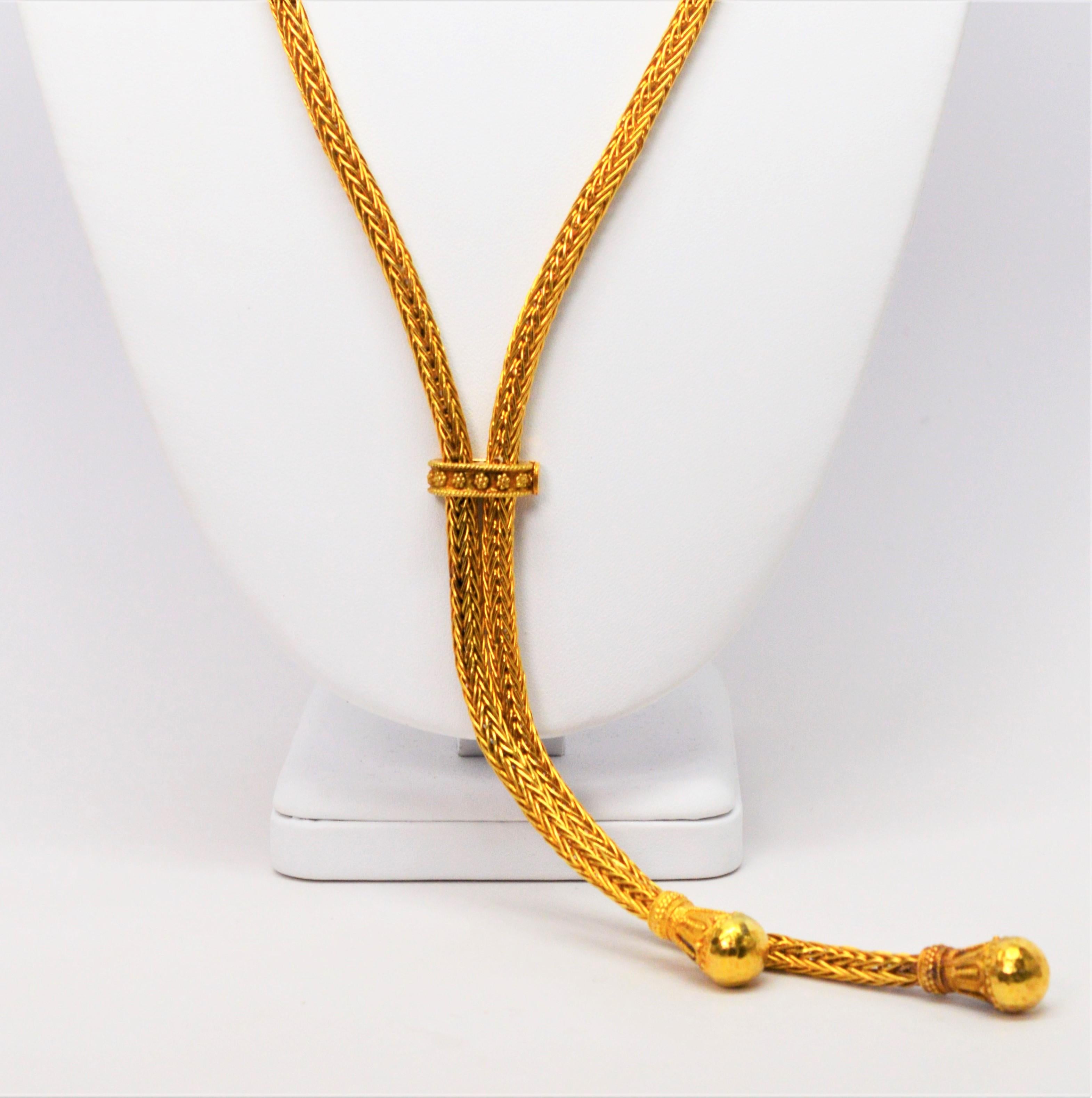 Truly a statement piece, in brilliant eighteen karat 18K yellow gold, this substantial woven rope chain is thirty three inches in length and is outfitted with an adjustable decorative gold slide creating a lariat style necklace. Each end of the 5mm