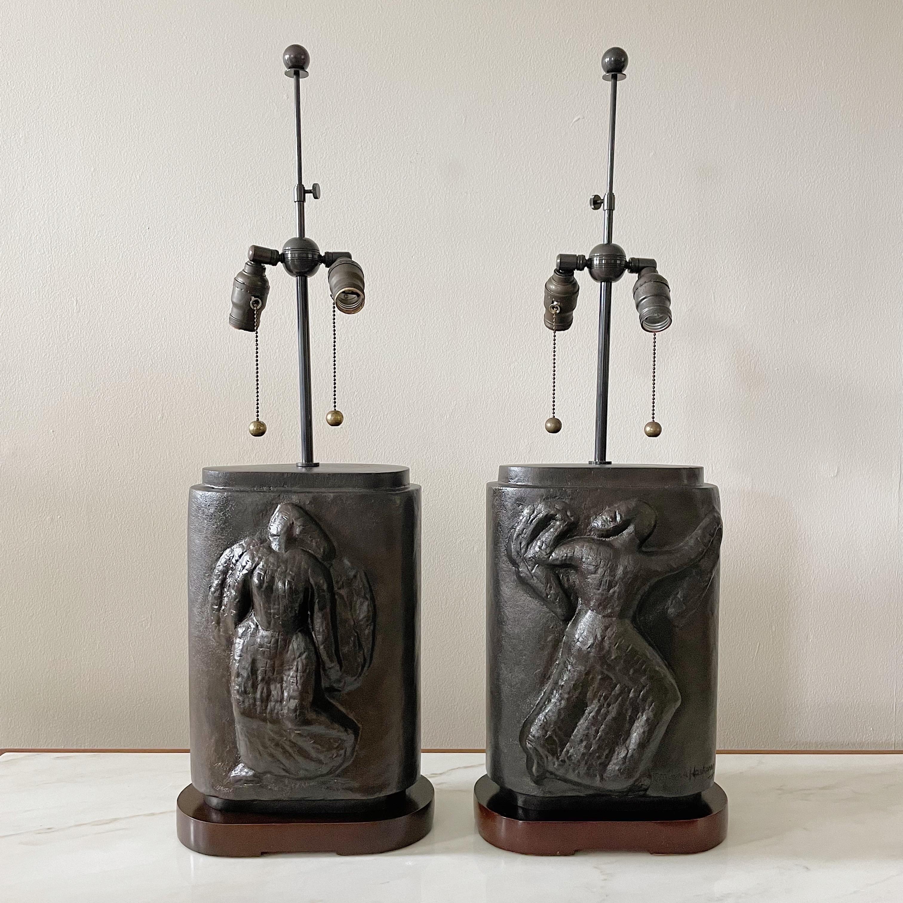 Pair of modernist 1930's sculptural bronze table lamps by WPA Artist Minna Harkavy. Raised figural reliefs on both sides of the lamps, with original wood bases. These lamps are extremely heavy thick cast bronze. Recently rewired with brown French