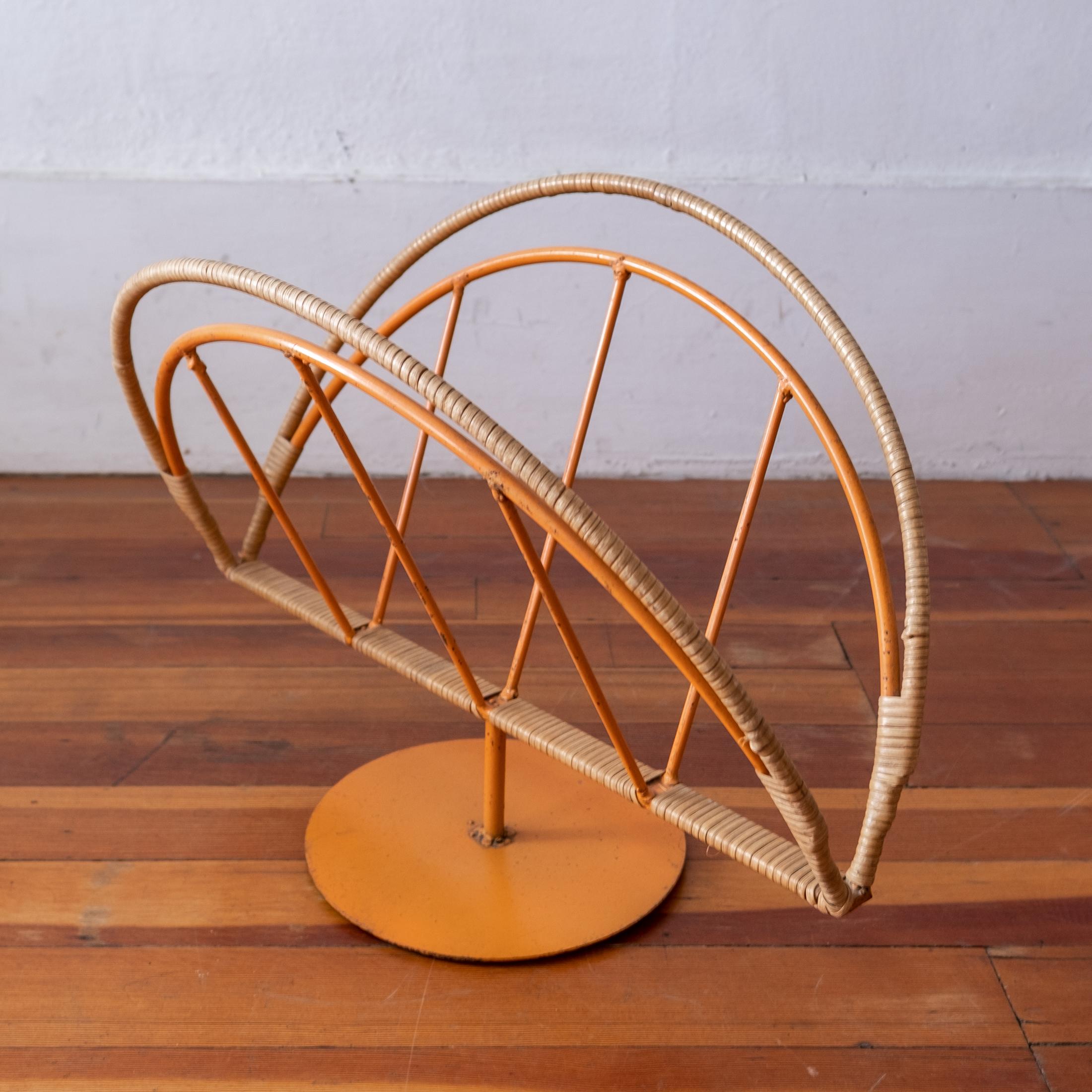 Wrapped cane and iron magazine rack by Arthur Umanoff for Raymor. Original orange enamel finish. A sturdy and functional piece.
