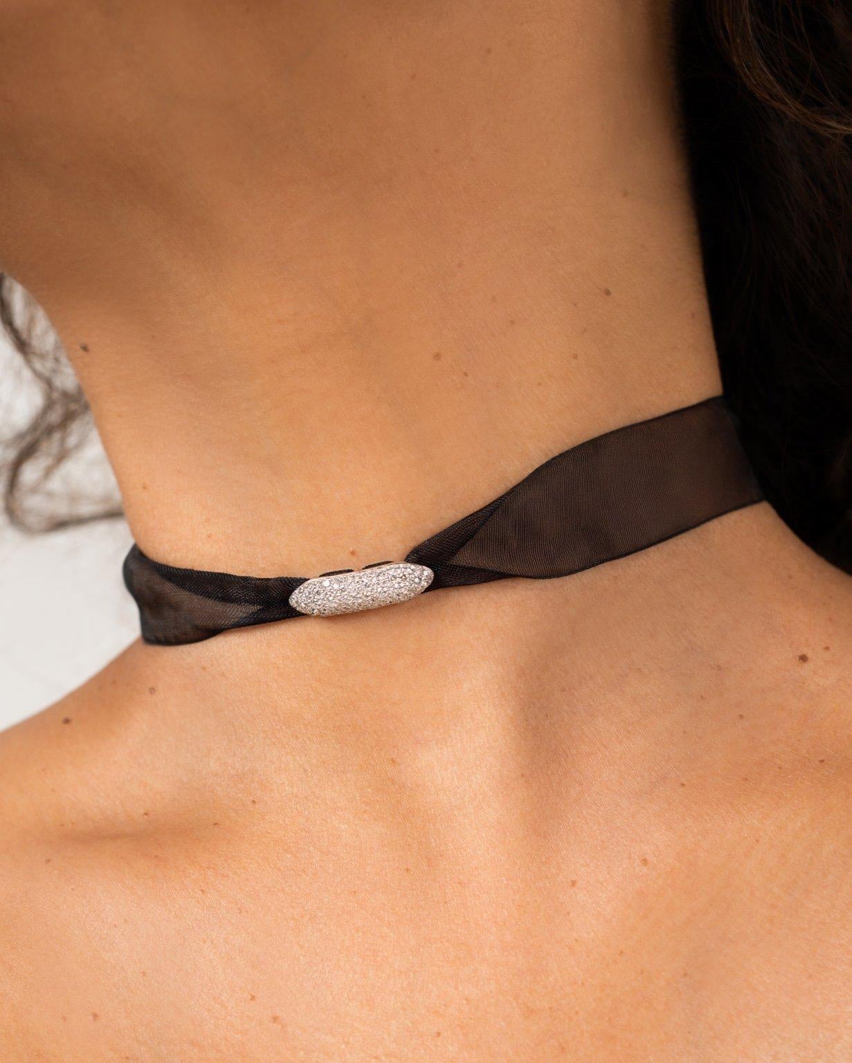 Il pezzo Wrapt in Diamonds è un design versatile che può essere indossato sia come girocollo aderente che come bracciale. È realizzato in oro 18 carati con diamanti rotondi naturali incastonati, mentre il cuore del pezzo è in tessuto chiffon che gli