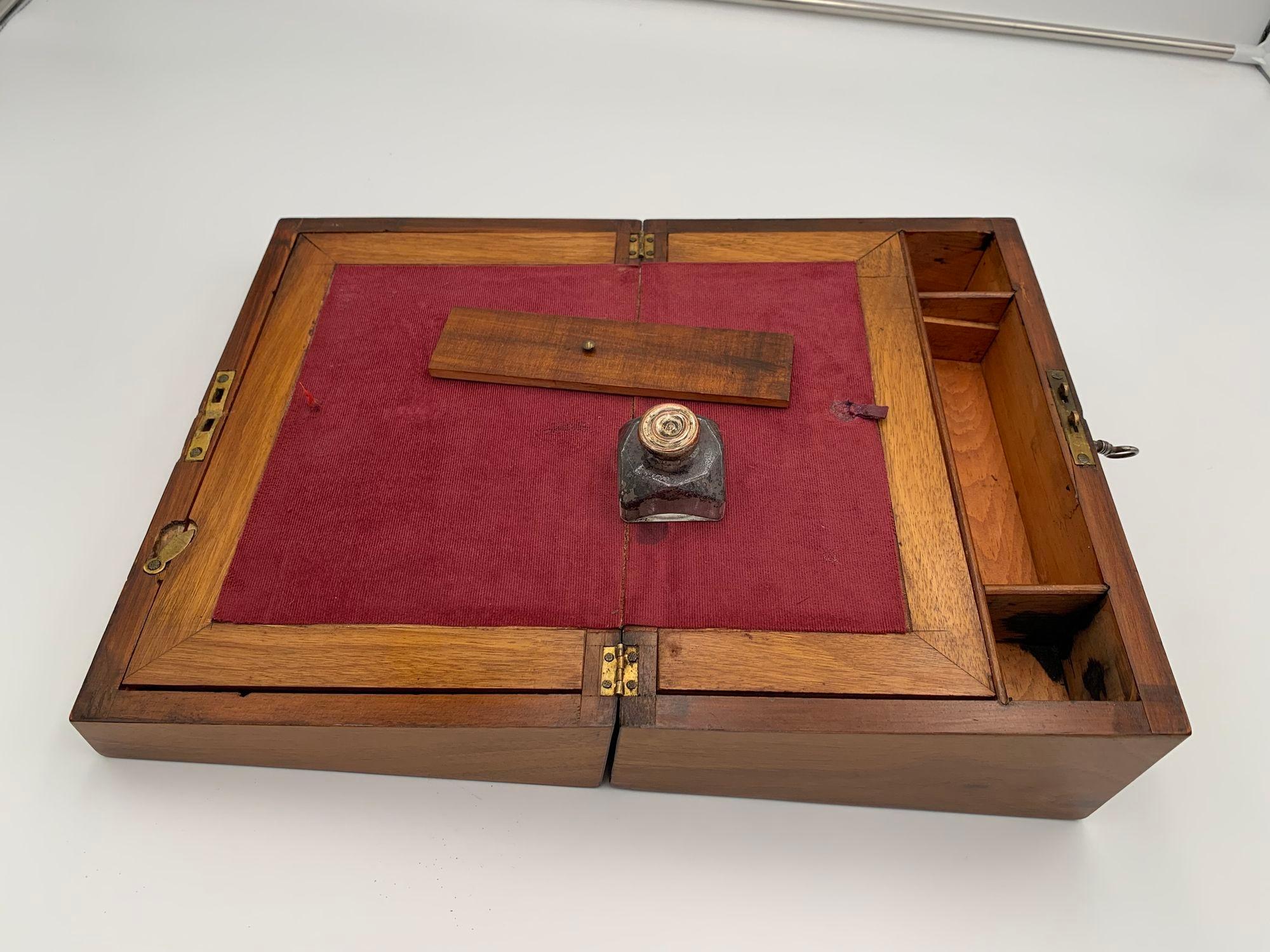 Beautiful antique writing box from the historicism / Victorian style from England, 2nd half of the 19th century.
 
Walnut veneered inlaid with various colored woods. Can be opened with an inclined writing surface. Old glass inkwell and red felt.