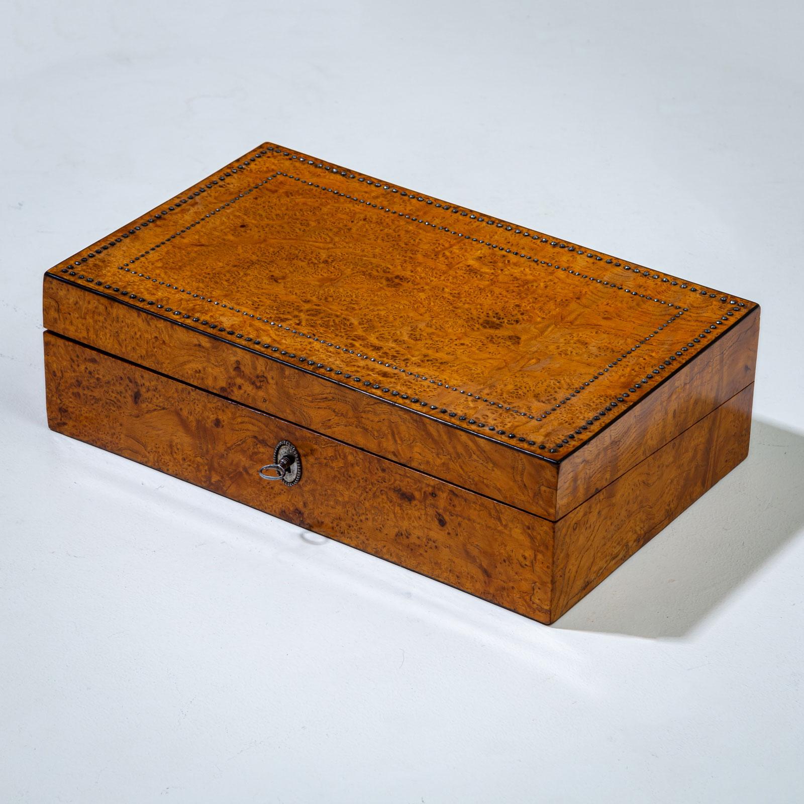 Small writing casket with thuja root veneer and surrounding steel-cut decoration. The casket is lockable and features an interior compartment for an inkwell, blotting sand, and a quill holder. The fold-out writing surface is covered with green felt.